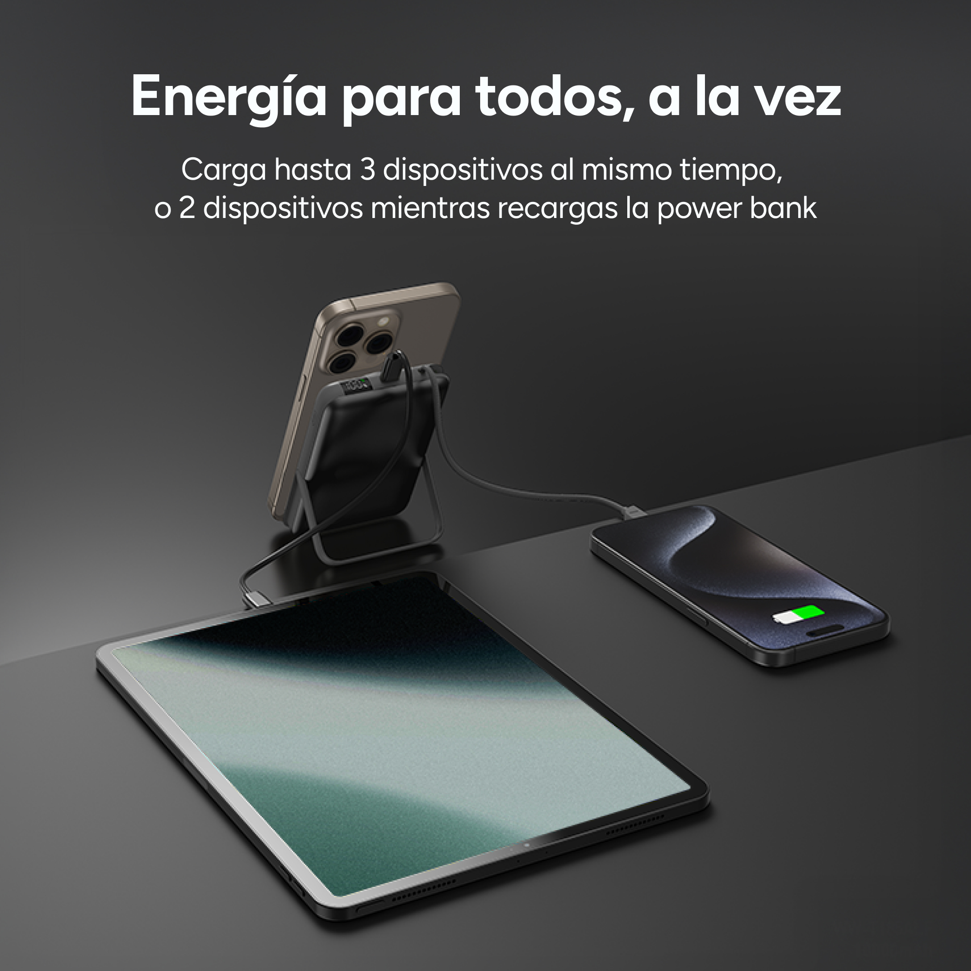 Se muestra un teléfono, una tableta y un banco de energía, con el teléfono cargándose y la tableta cerca, sobre una superficie oscura.