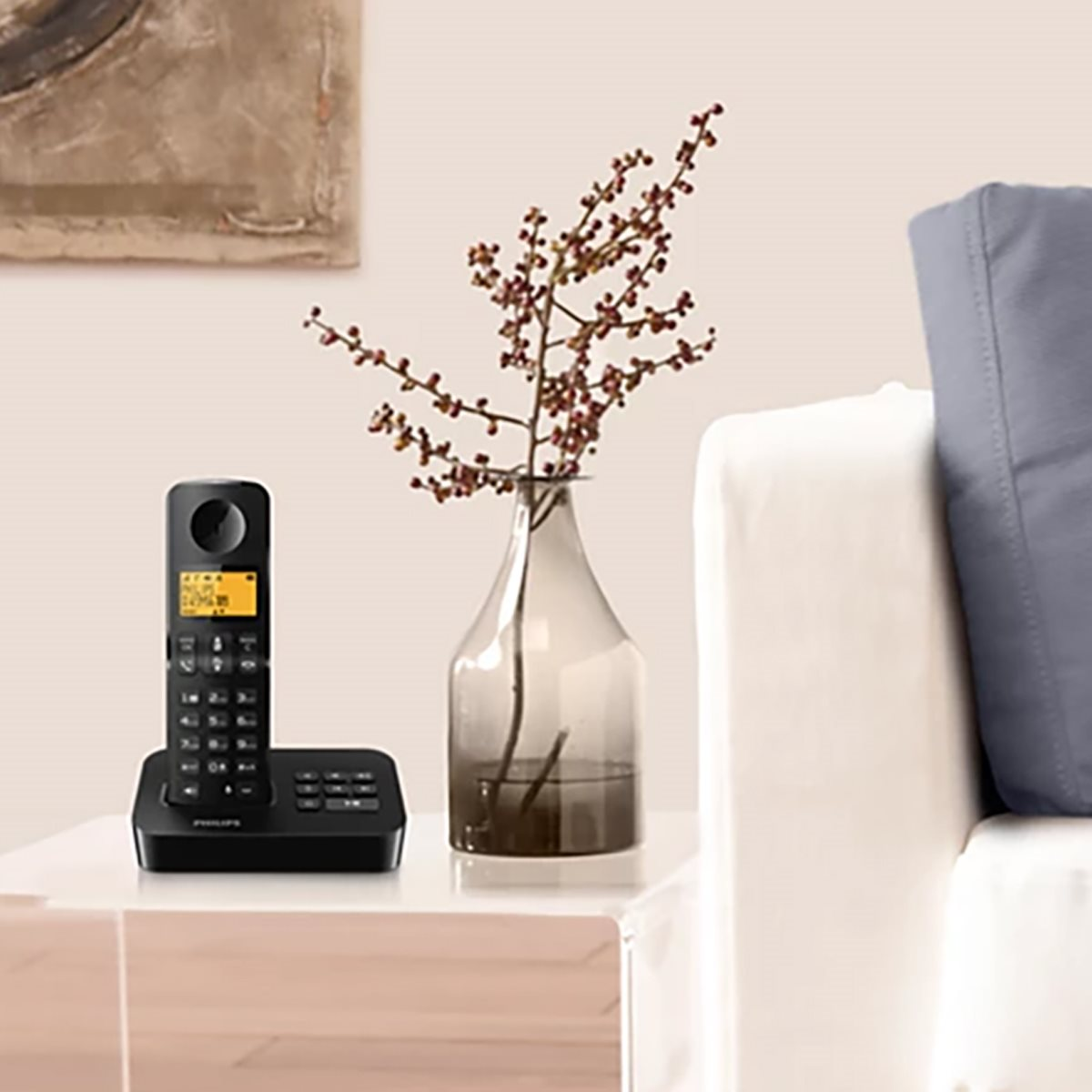 Ein schwarzes Telefon auf einer Basis mit Blumenvase und Couch, im Hintergrund ein Gemälde.