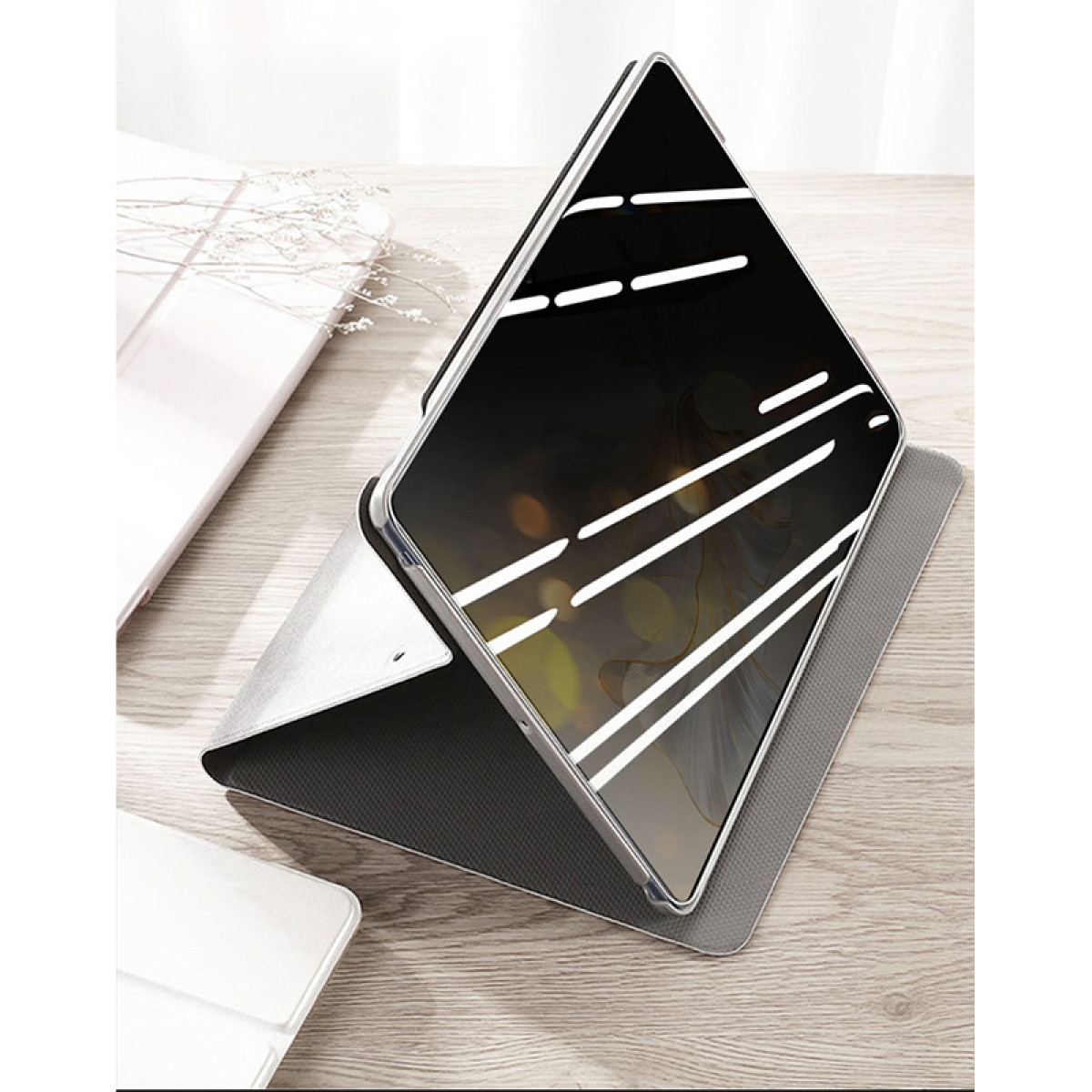 Ekran tabletu znajduje się w etui ochronnym. Tablet jest pod kątem na drewnianej powierzchni, inne przedmioty wokół.