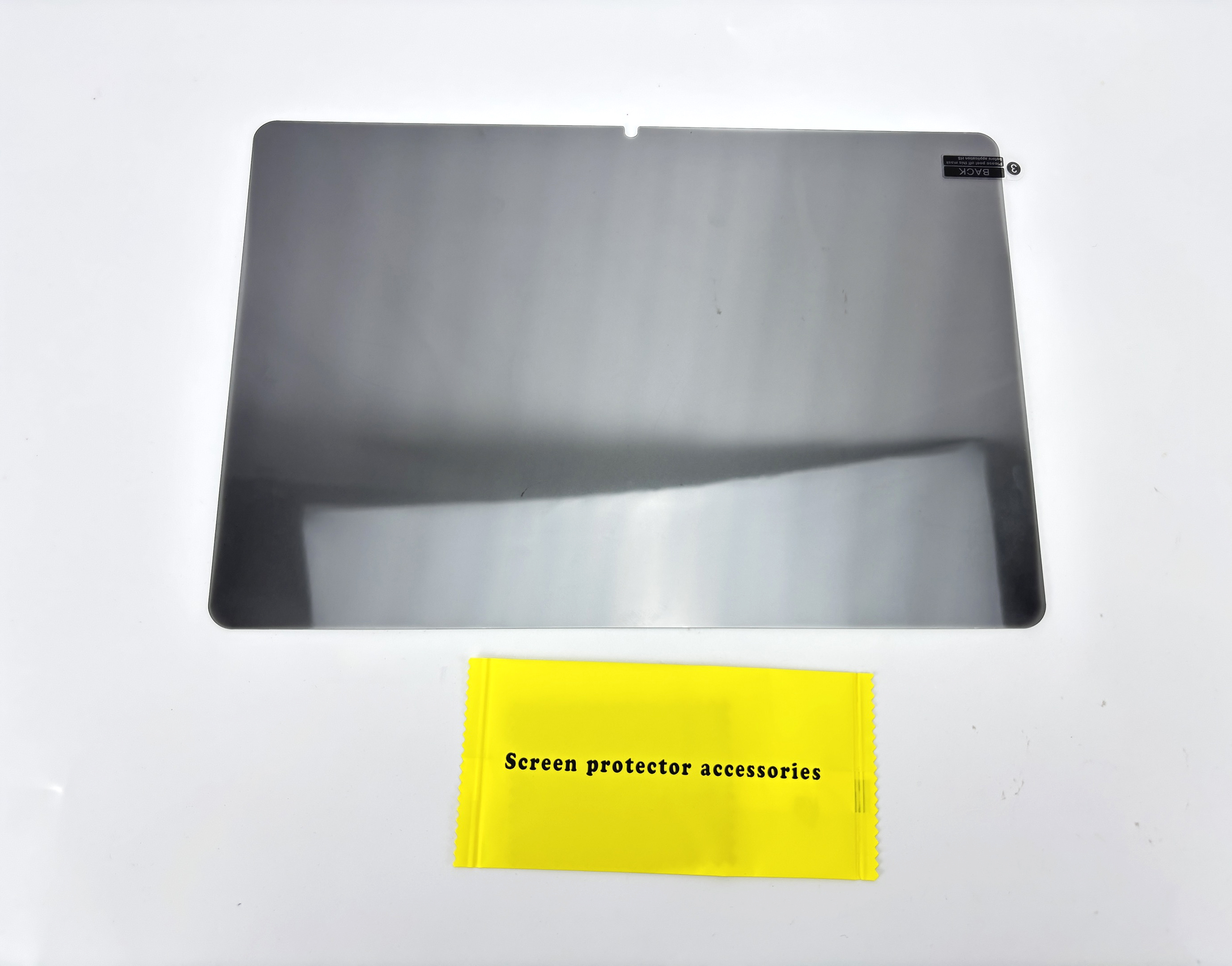 Szara osłona ekranu i żółte opakowanie akcesoriów do osłony ekranu na białej powierzchni.