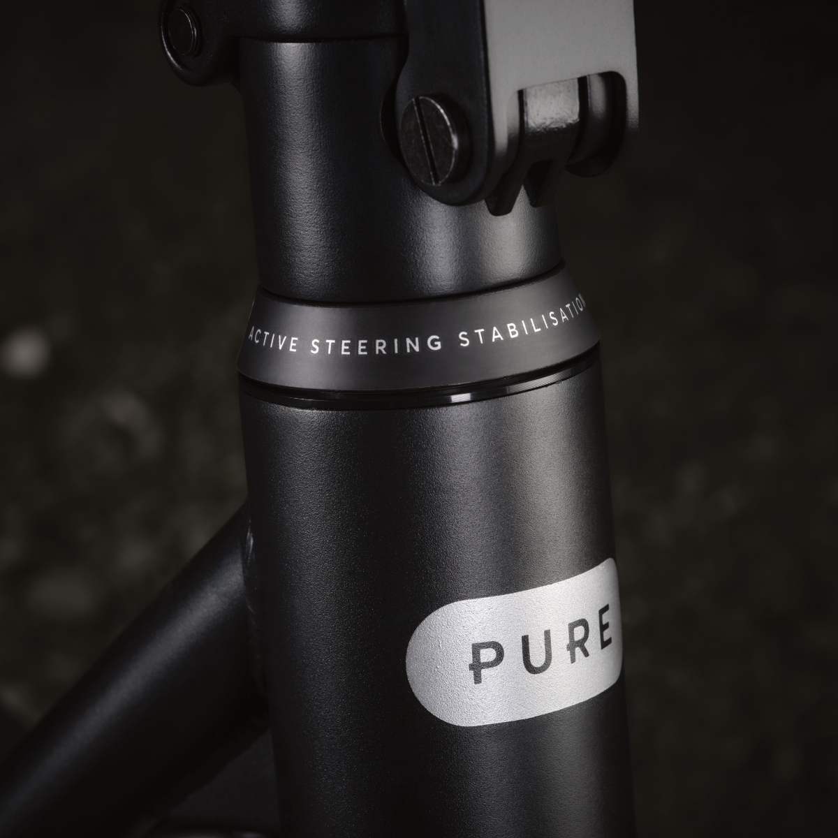 Nahaufnahme eines schwarzen Rollerstiels mit 'PURE'-Logo und Text 'ACTIVE STEERING STABILISATION'. Dunkler Hintergrund.