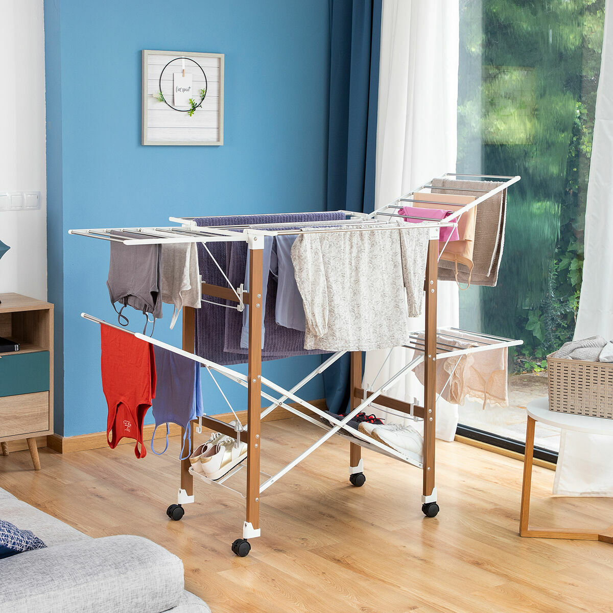 Ein Wäscheständer mit Kleidung in einem Raum mit blauen Wänden, einem Fenster und Holzboden.