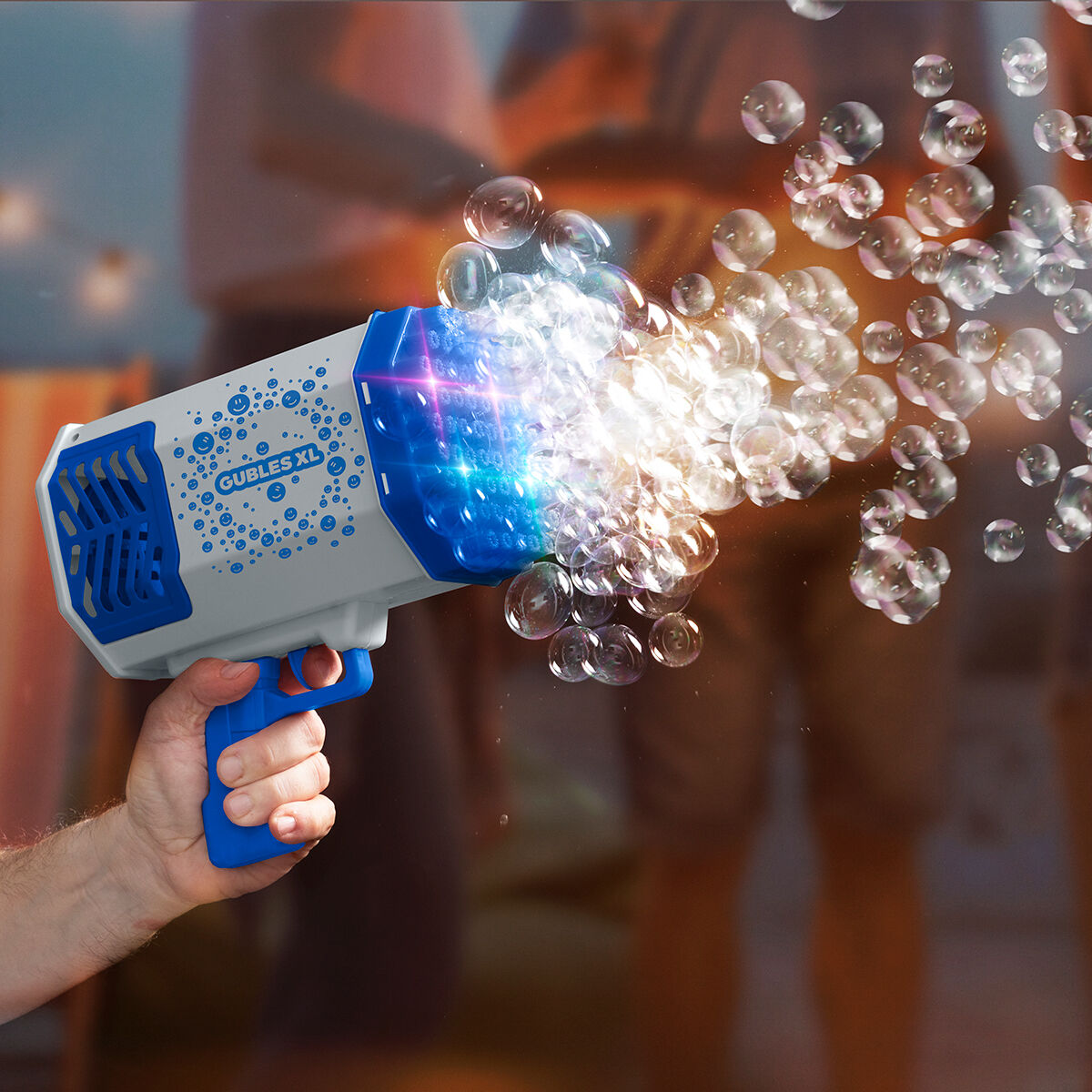 Eine Person hält eine blau-weiße Seifenblasenpistole und schießt viele Blasen in die Luft.