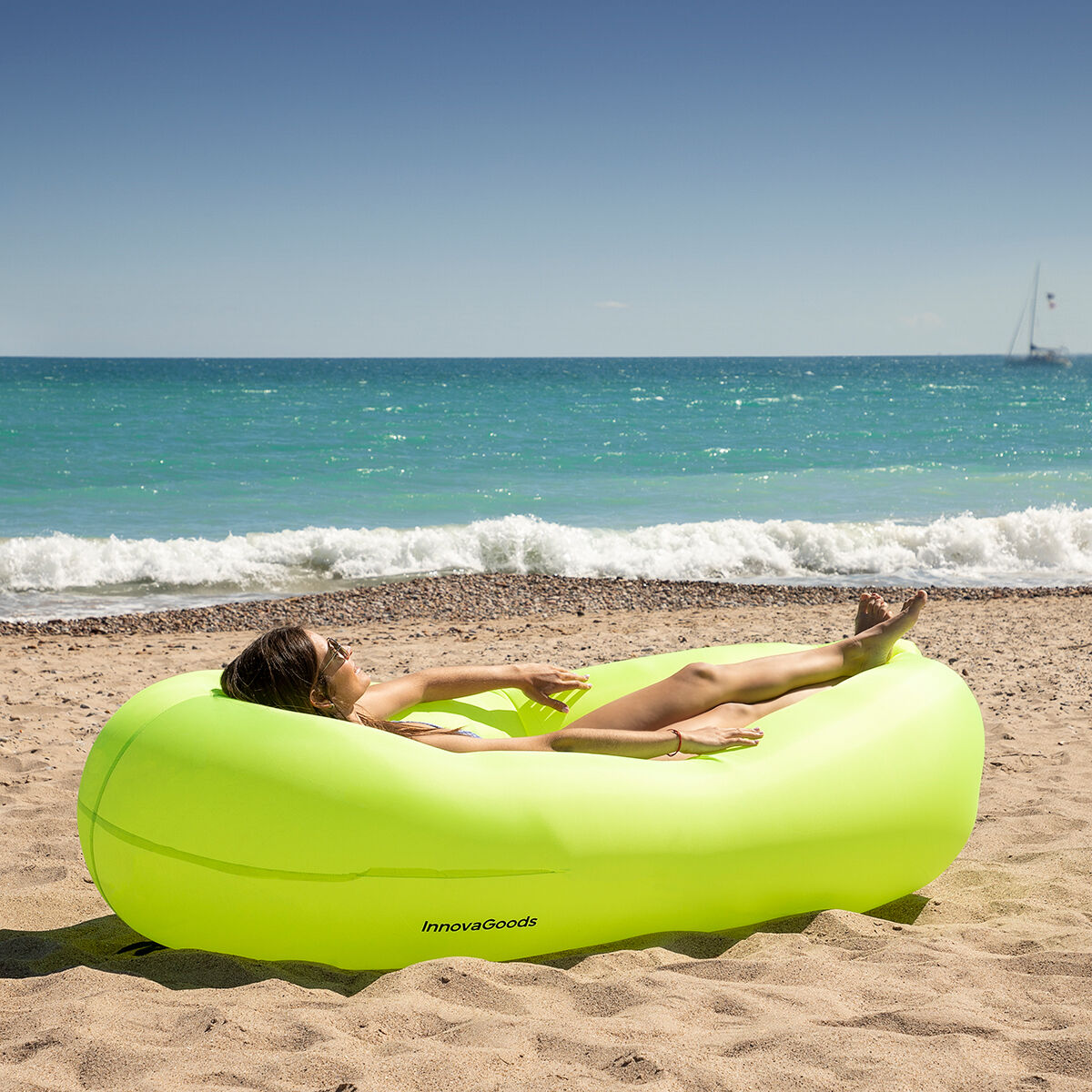 Eine Frau liegt auf einer gelben, aufblasbaren Liege am Strand.