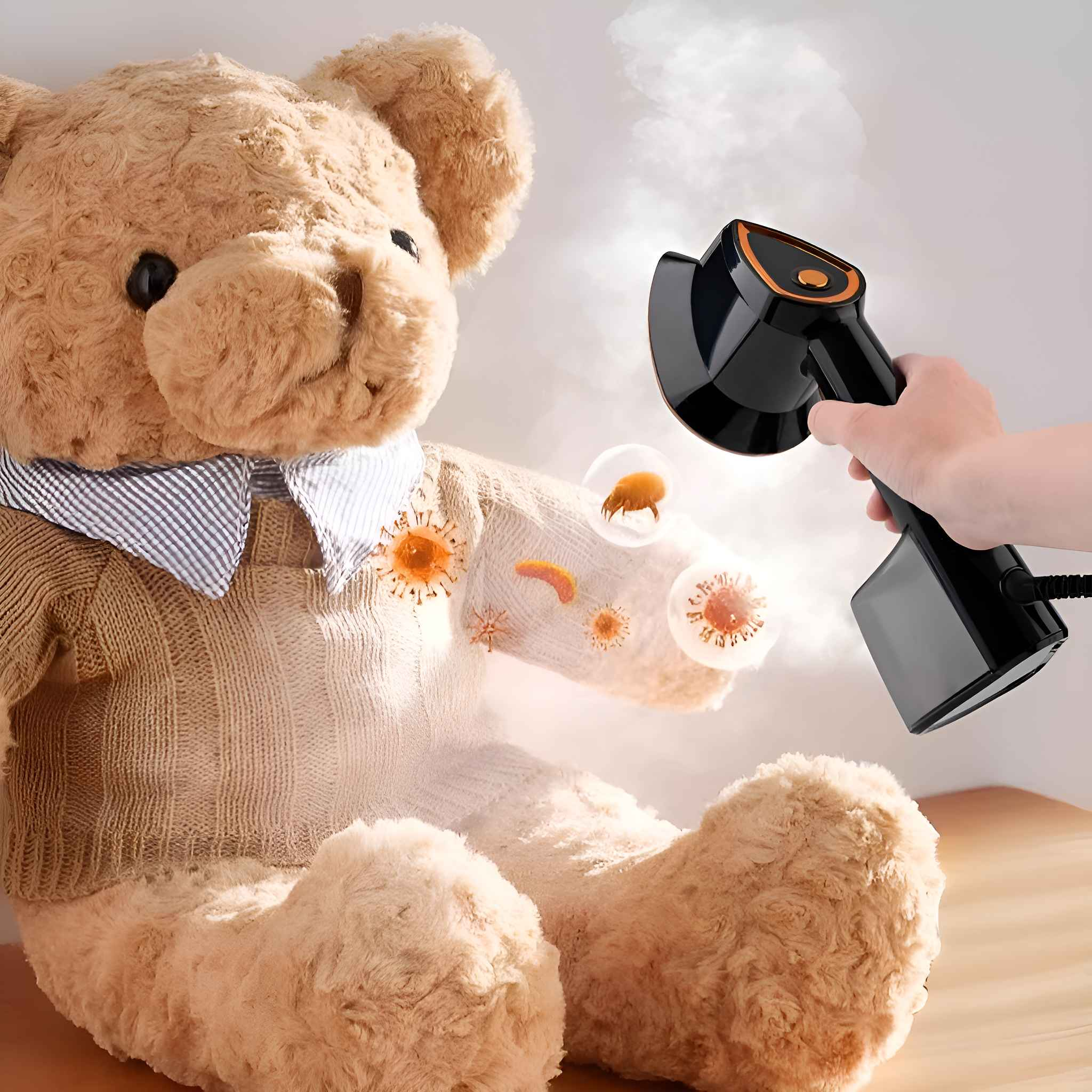 Ein Teddybär wird mit einem schwarz-orangen Kleidungsdampfer gedämpft. Keime werden auf dem Bären visualisiert.