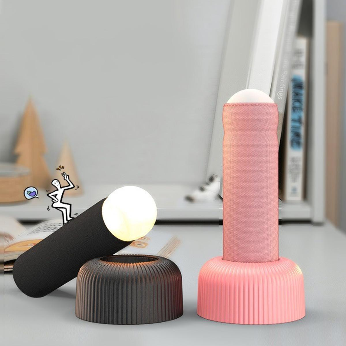Zwei Lampendesigns. Eine schwarze zylindrische Lampe und eine rosa zylindrische Lampe mit passendem Sockel. Eine kleine Cartoonfigur.