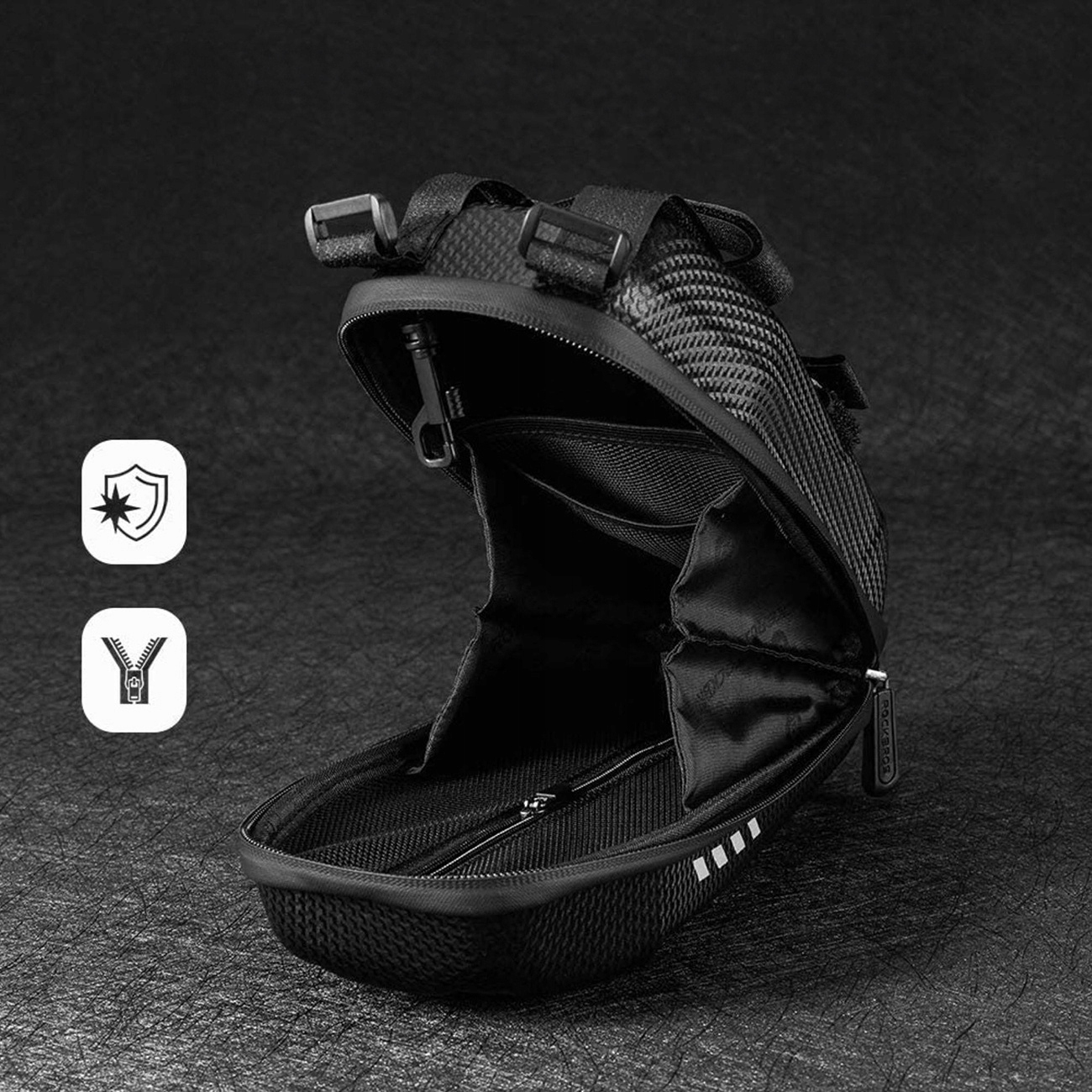 Otwarta czarna torba na skuter z przedmiotami w środku, z logo i ikonami bezpieczeństwa na czarnym tle.