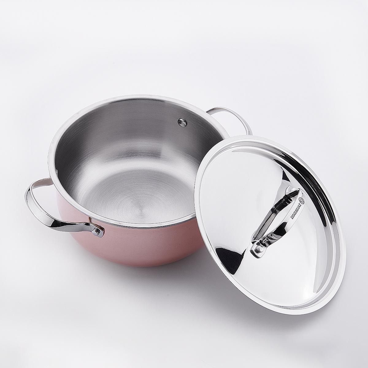 Een roze pan met zilveren handgrepen, zittend naast zijn zilveren deksel op een wit oppervlak.