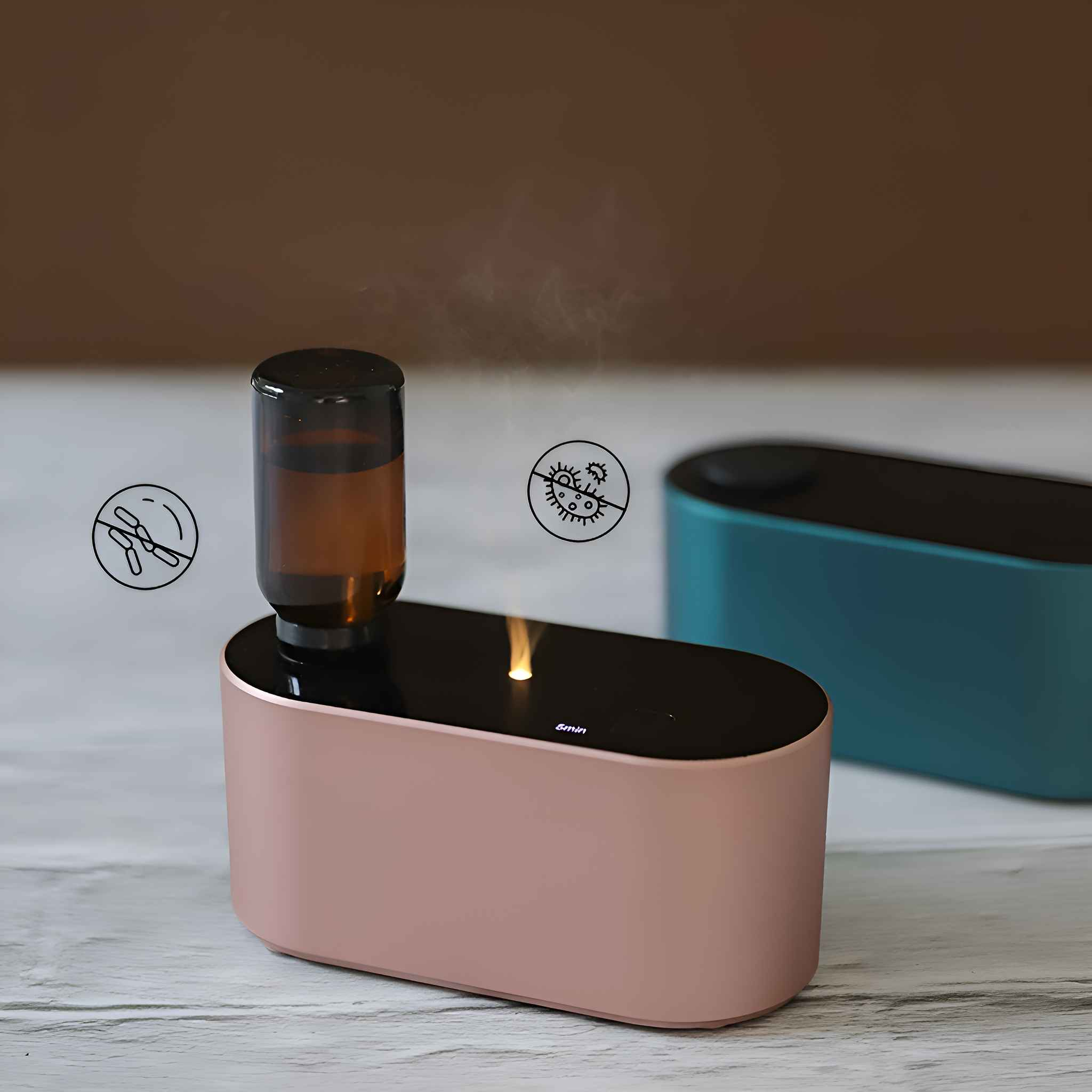 Ein rosa Aromadiffusor mit einer eingesetzten braunen Flasche und Zeichnungen von Keimen. Dahinter ein teal Diffusor.