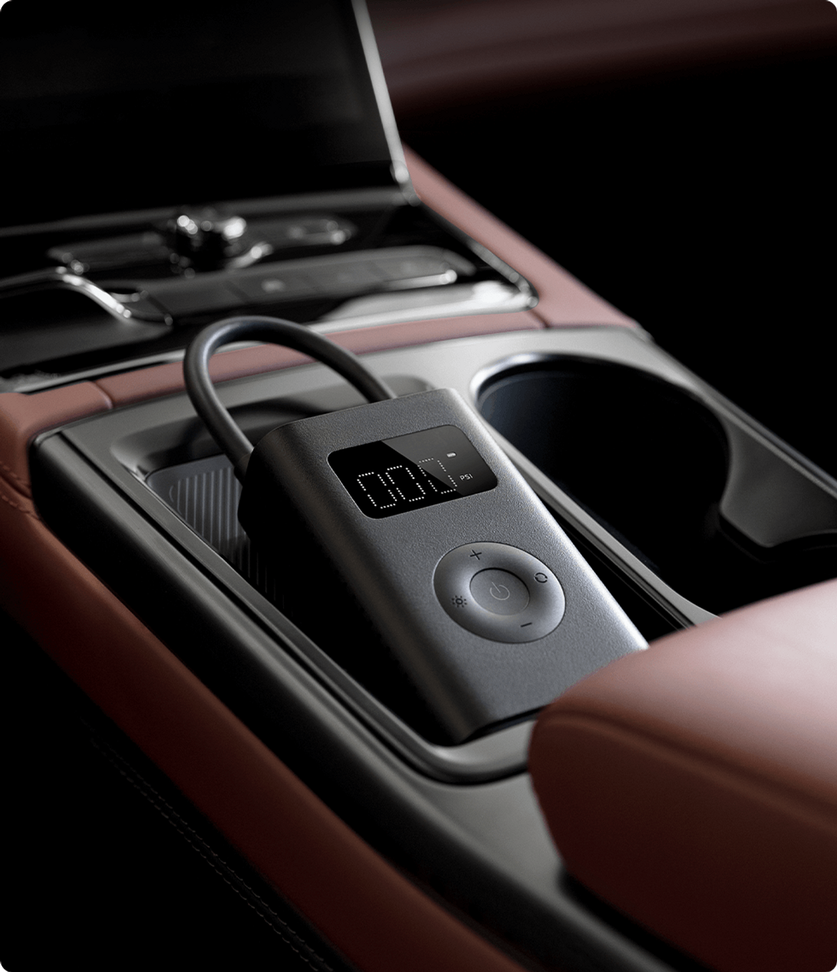 Araba konsolunda gri hava pompası. Pompa, PSI gösteren dijital bir ekrana sahip. Kahverengi deri görünüyor.