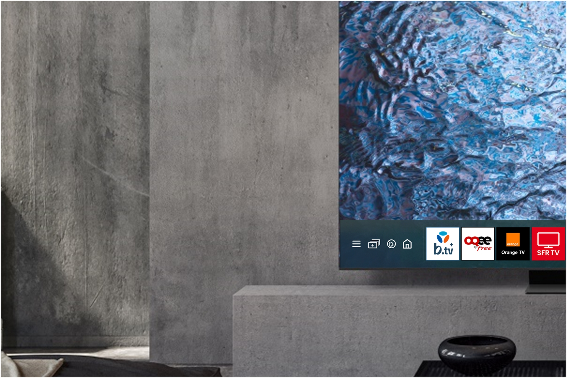 Una pantalla de TV moderna contra una pared gris texturizada con una interfaz simple.