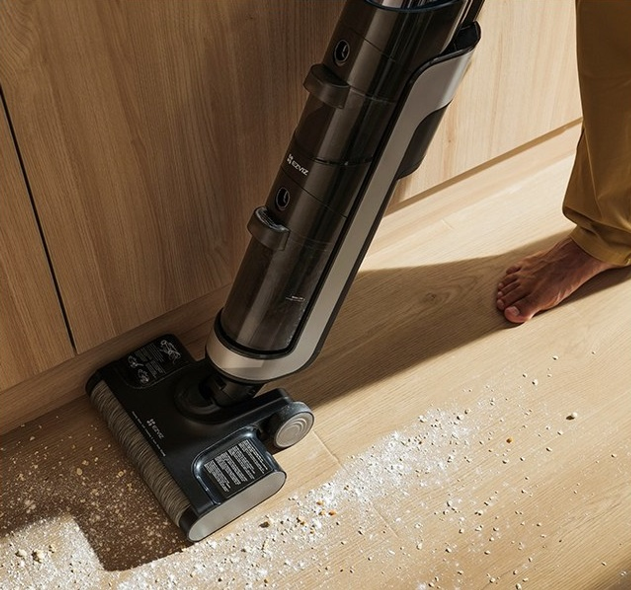 Una persona sta passando l'aspirapolvere su un pavimento di legno con un aspirapolvere portatile.