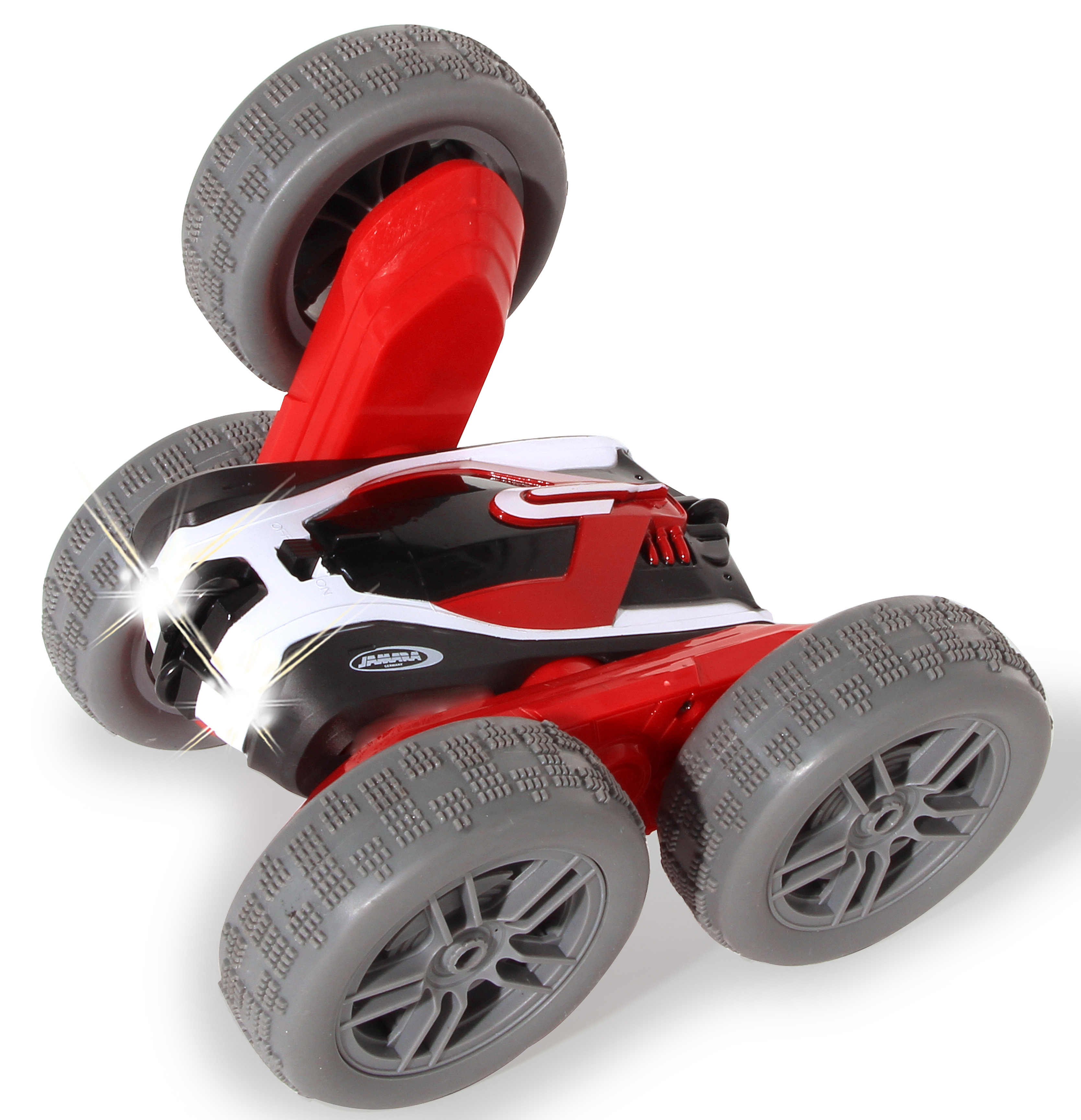 Ein rotes, schwarzes und weißes Spielzeugauto ist abgewinkelt, wobei die Räder nach oben zeigen. Das Auto hat graue Reifen und die Scheinwerfer sind an.