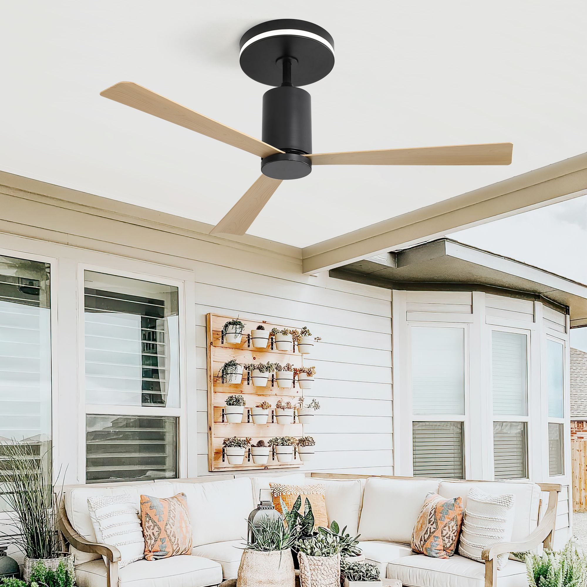 Außenbereich mit Deckenventilator, Sitzgelegenheiten und einer Holzwand mit Pflanzen.