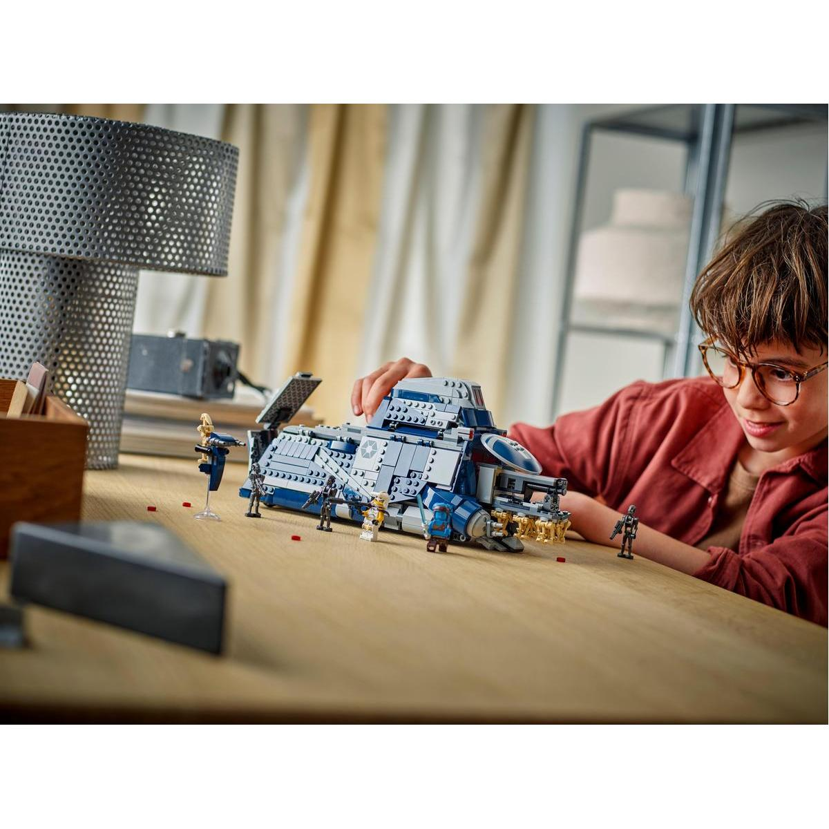 Chłopiec bawiący się zestawem LEGO przedstawiającym niebiesko-biały statek kosmiczny z minifigurkami.