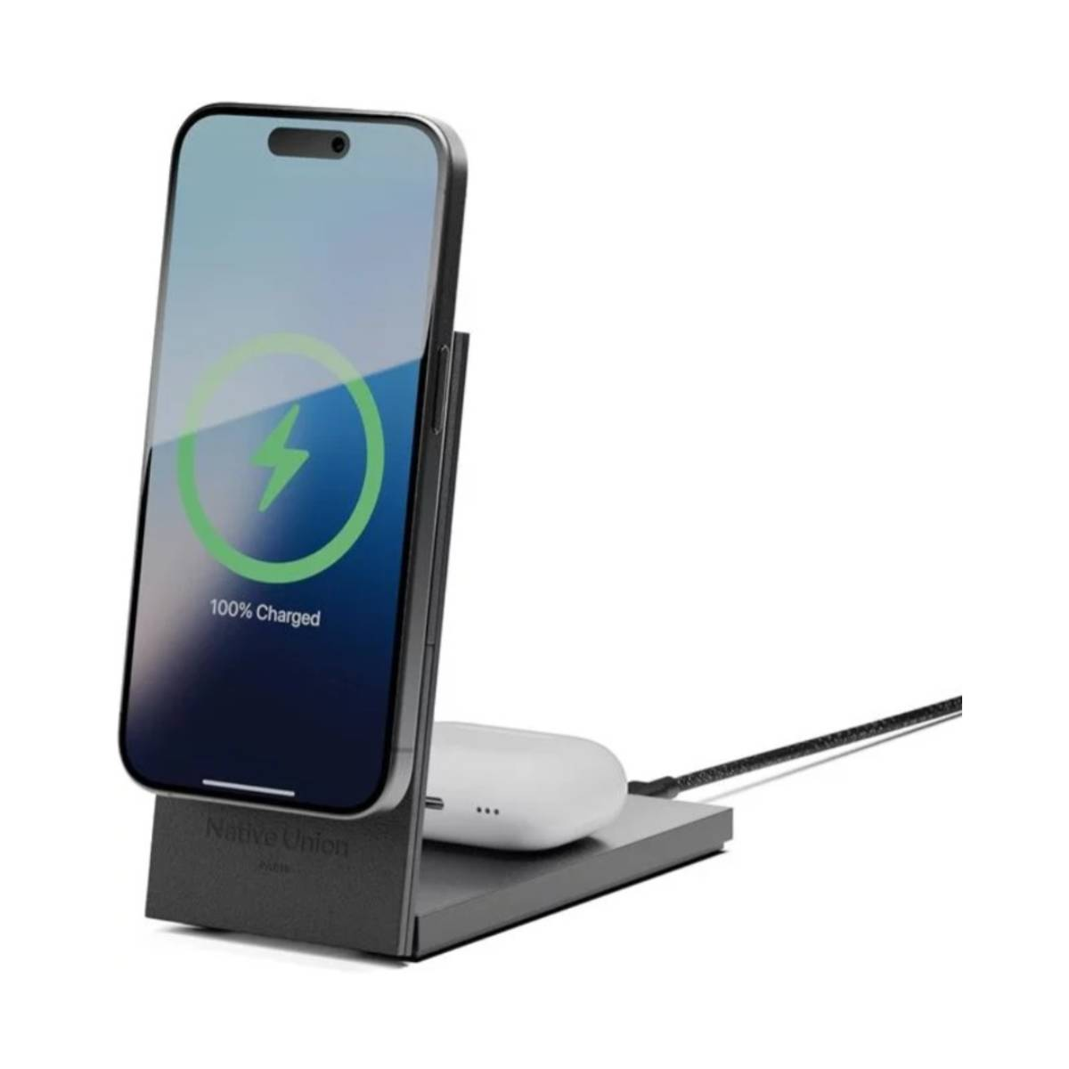 iPhone lädt auf einem Ständer, mit AirPods, alles auf schwarzer Basis. Der Bildschirm zeigt 100 % geladen.