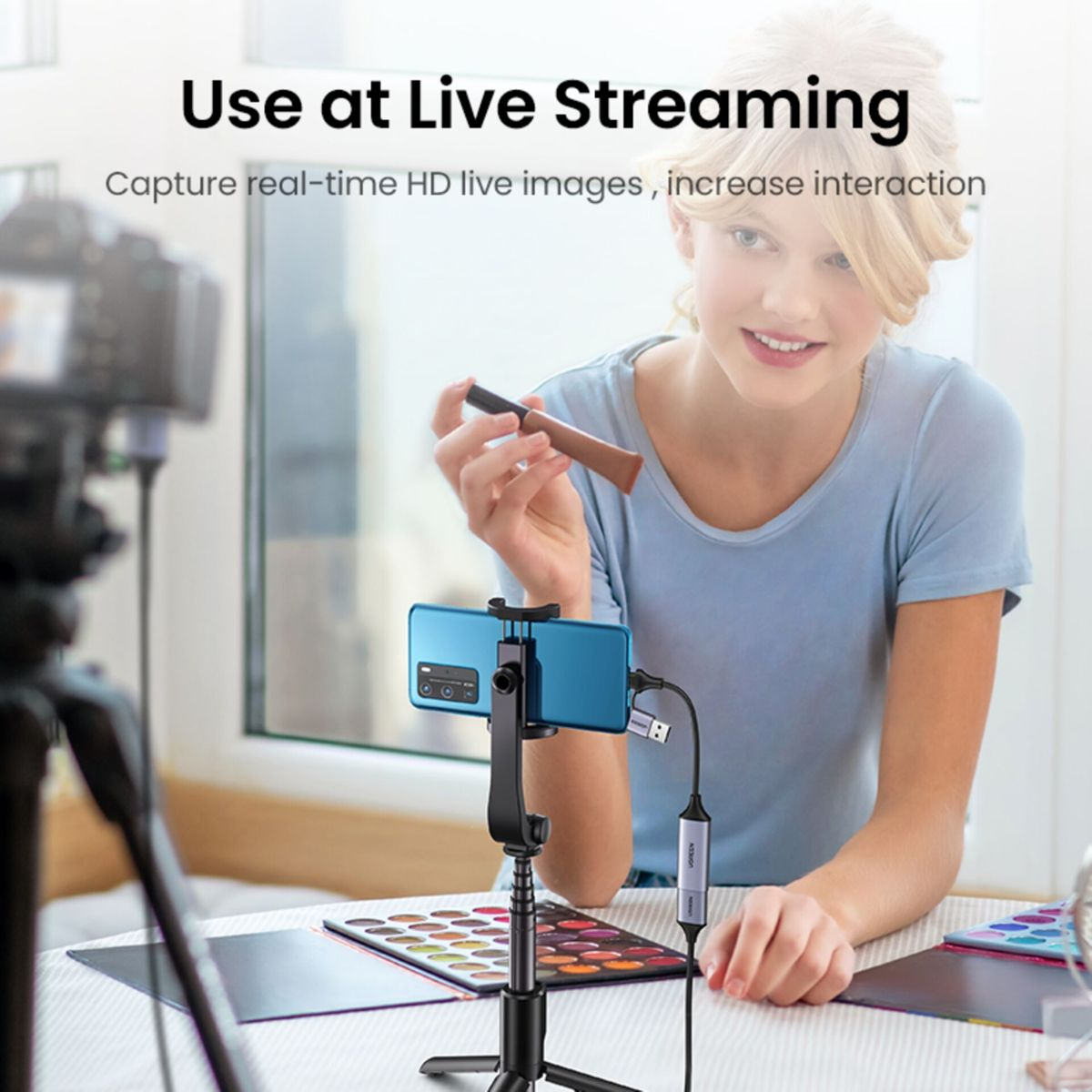 Frau, die ihr Telefon für Live-Streaming verwendet. Telefon ist per Kabel mit Kamera verbunden.