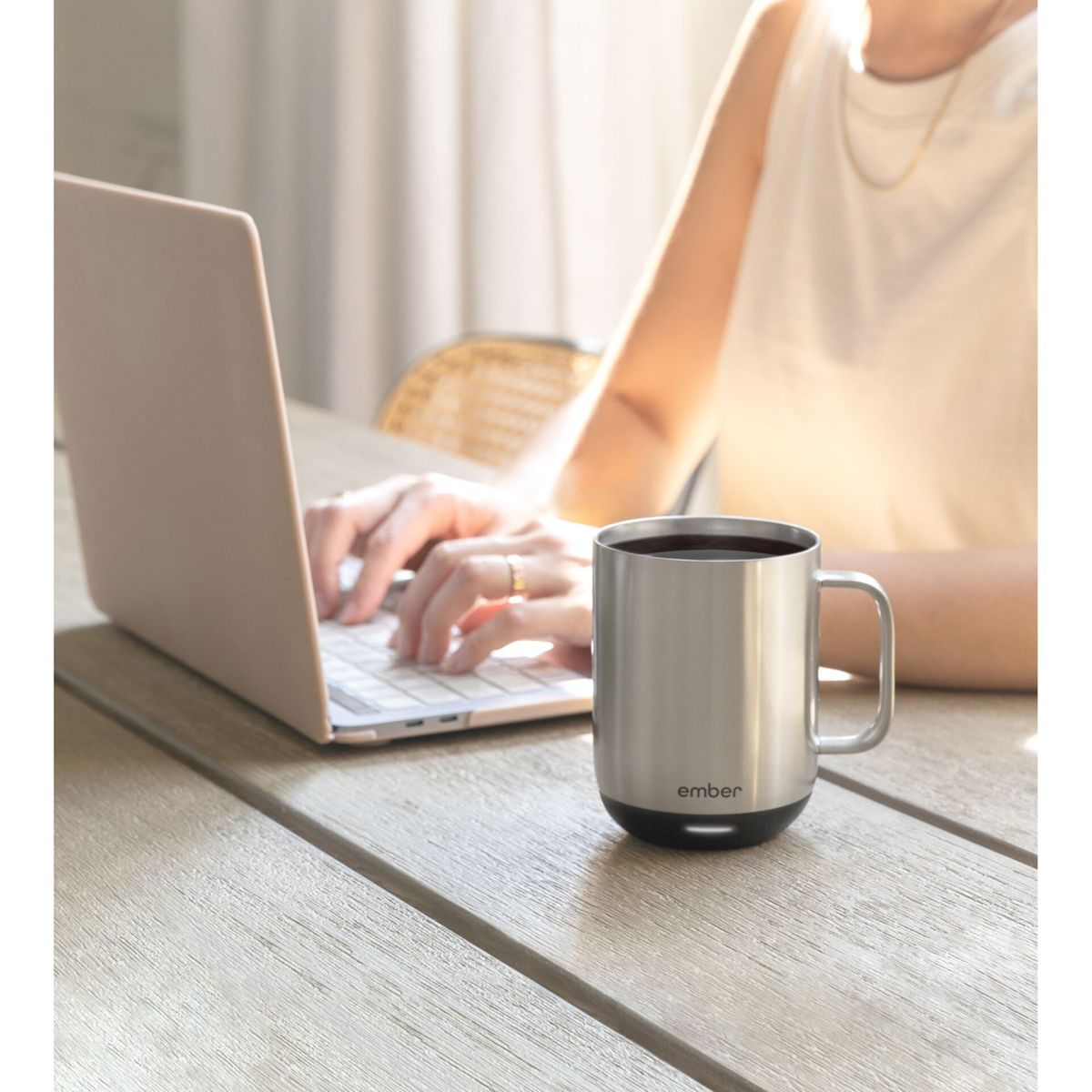 Una persona usa una computadora portátil, una taza está sobre la mesa. Fondo blanco.