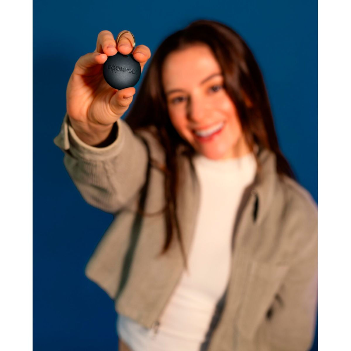 Kobieta trzyma małą czarną kulę na tle niebieskiego tła. Na kuli jest tekst.