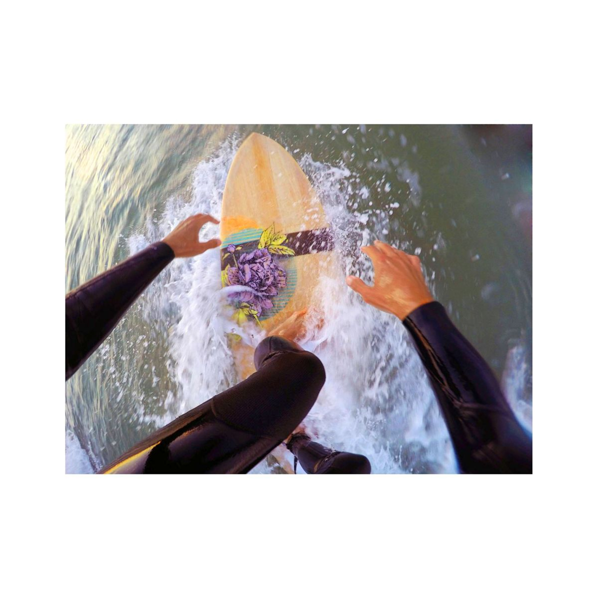 Osoba surfująca na desce surfingowej w oceanie. Widoczne są dłonie, trzymające deskę.