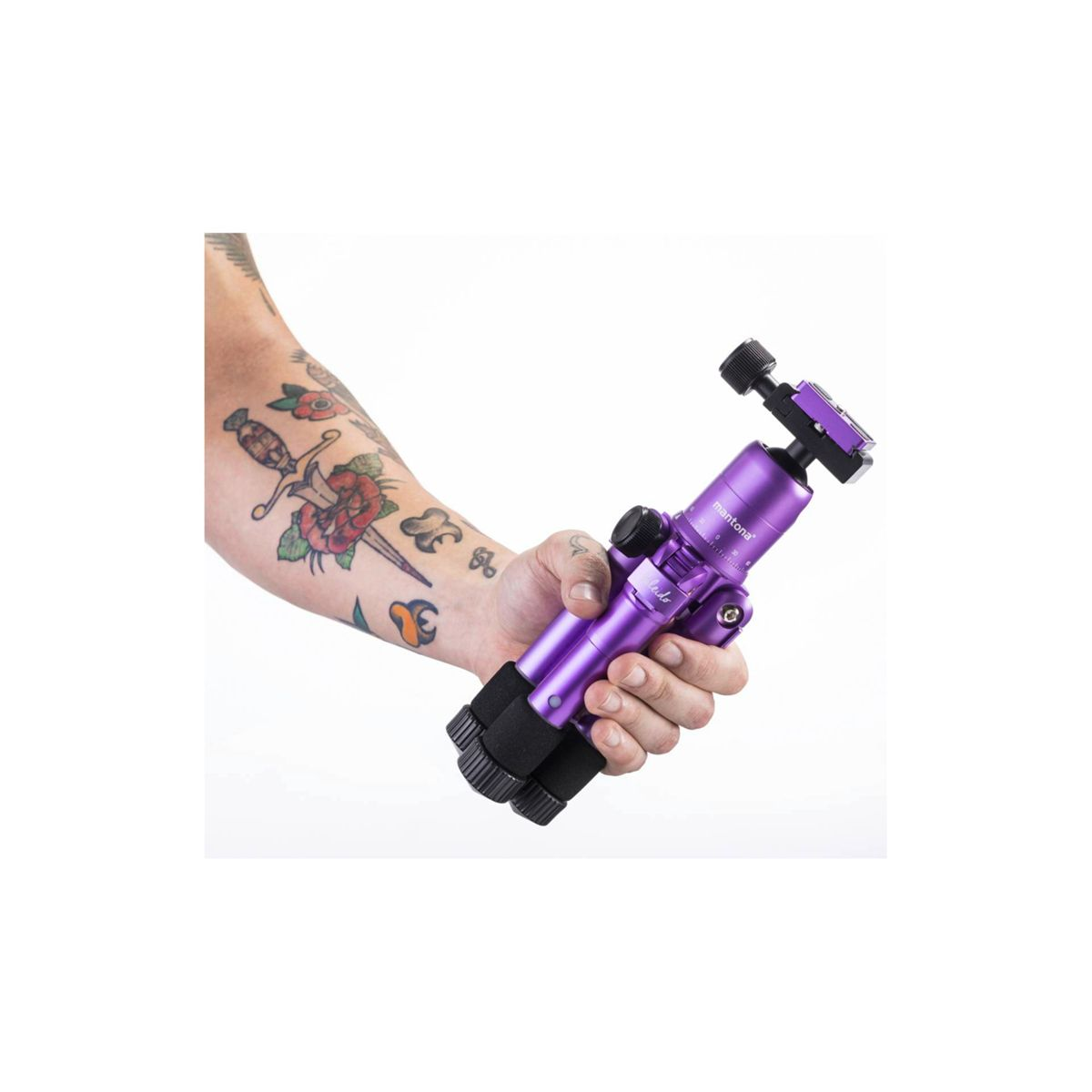 Ramię z tatuażami trzymające fioletowy statyw. Białe tło.