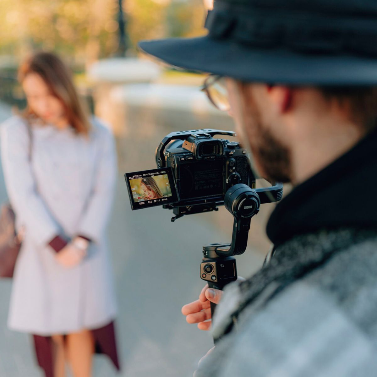Eine Person filmt eine andere Person mit einer Kamera auf einem Gimbal. Der Hintergrund ist unscharf.