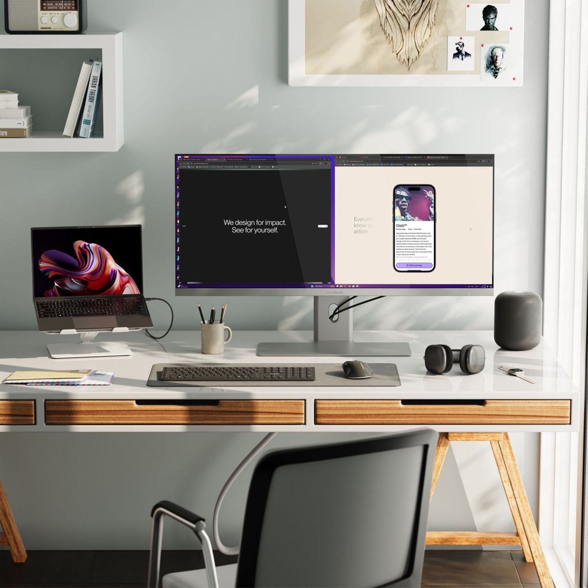 Ein Schreibtisch mit Laptop, Monitor und Telefon. Kunstwerke einer Person sind an der Wand. Der Schreibtisch ist weiß mit Holzbeinen.