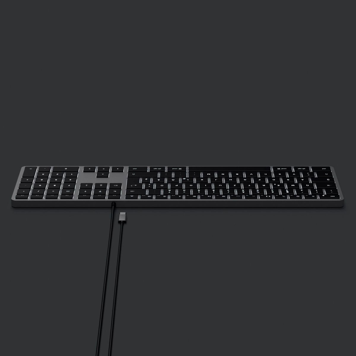Eine silberne Tastatur mit schwarzen Tasten. Das Kabel ist schwarz, mit einem USB-C-Anschluss. Der Hintergrund ist dunkelgrau.