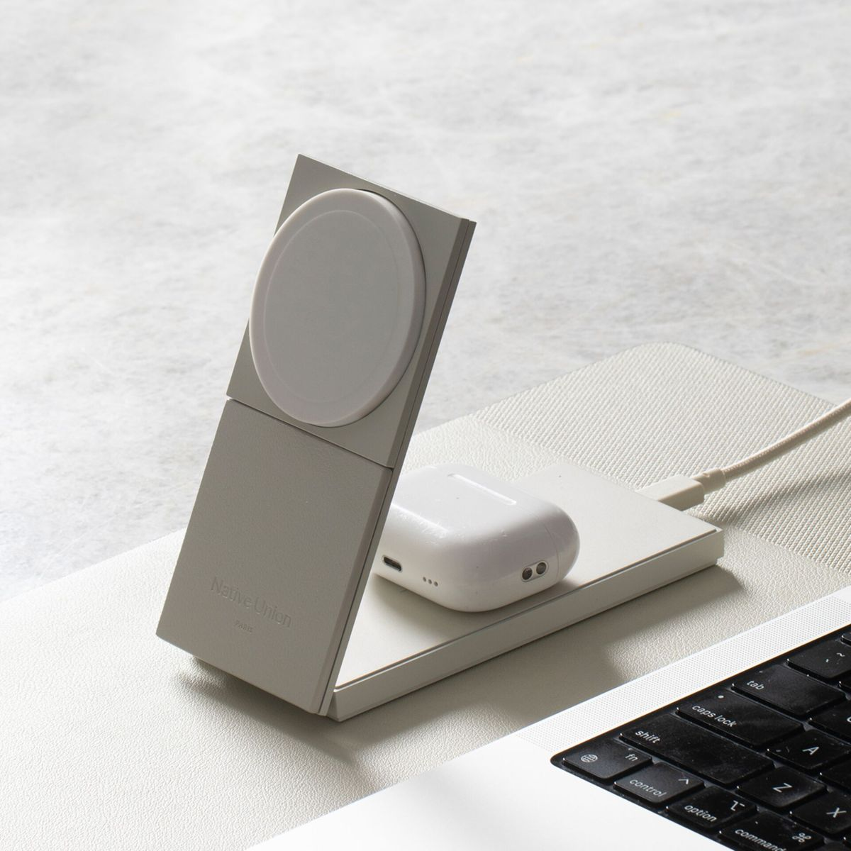 Ein Ladeständer mit einem weißen AirPods-Case und einem weißen Kreis. Er liegt auf einem Laptop.