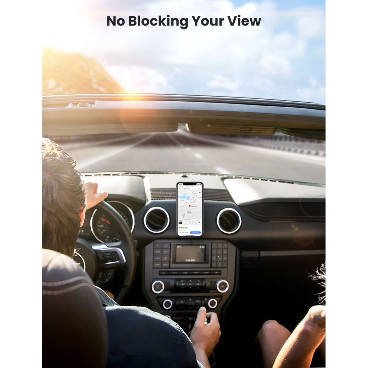 Telefon na desce rozdzielczej samochodu, z widoczną drogą przez przednią szybę.