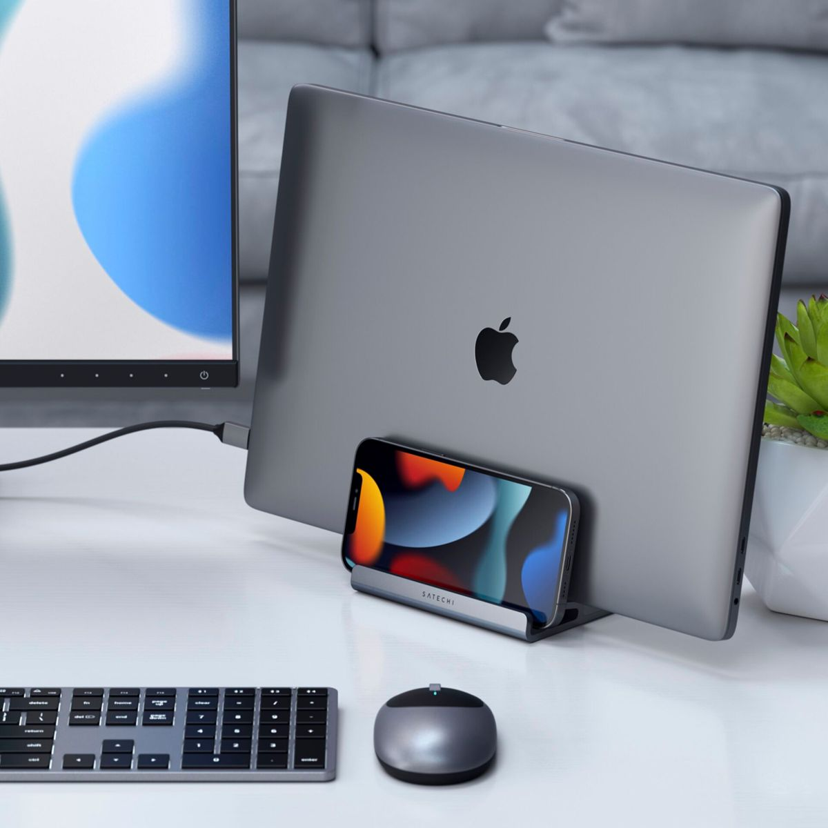 Laptop ze stojakiem na telefon, telefonem, myszą i klawiaturą na biurku.