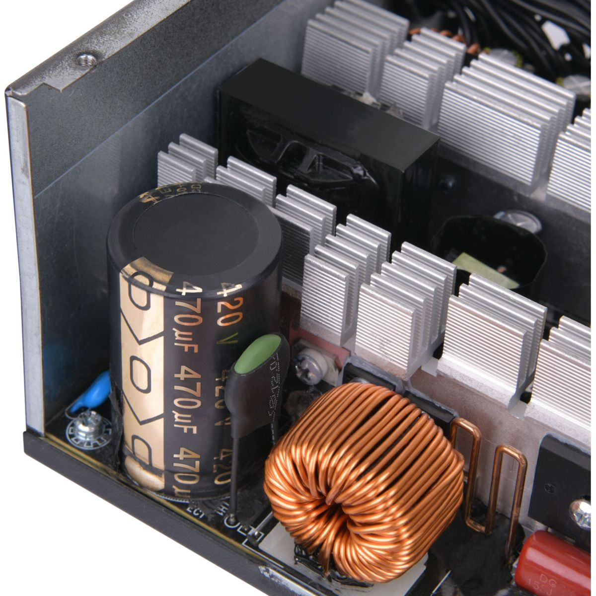 Wewnątrz zasilacza: kondensator, cewka, radiatory i inne elementy elektroniczne.