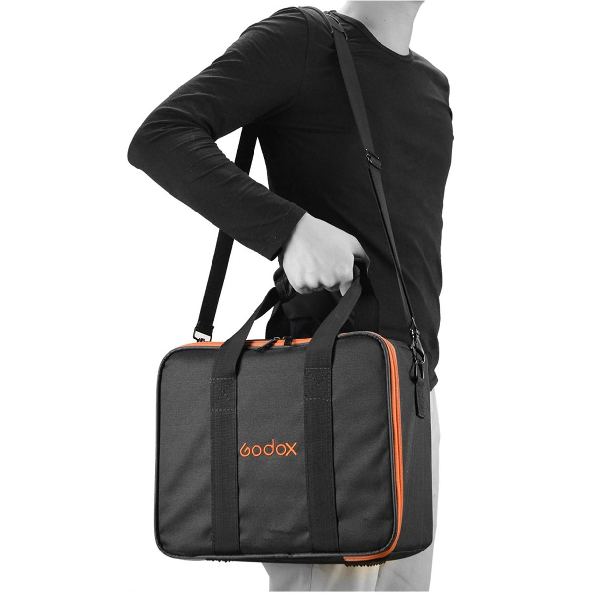 Eine Person hält eine schwarze Tasche mit orangenen Verzierungen. Die Tasche hat einen Schultergurt und einen Griff. Das Logo 'godox' ist sichtbar.