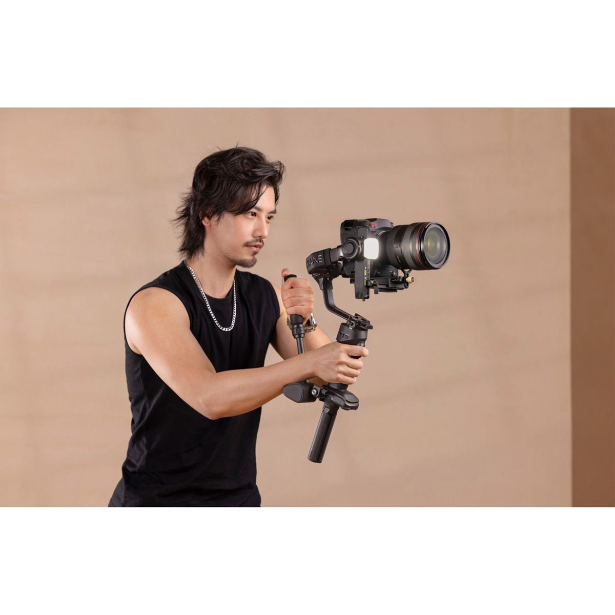 Eine Person, die eine Kamera auf einem Gimbal hält. Die Person trägt ein schwarzes Tanktop und hat lange Haare.