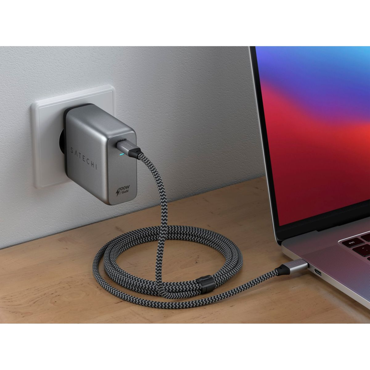 Un adattatore di alimentazione argento collegato a una presa a muro. Un cavo è collegato a un laptop.