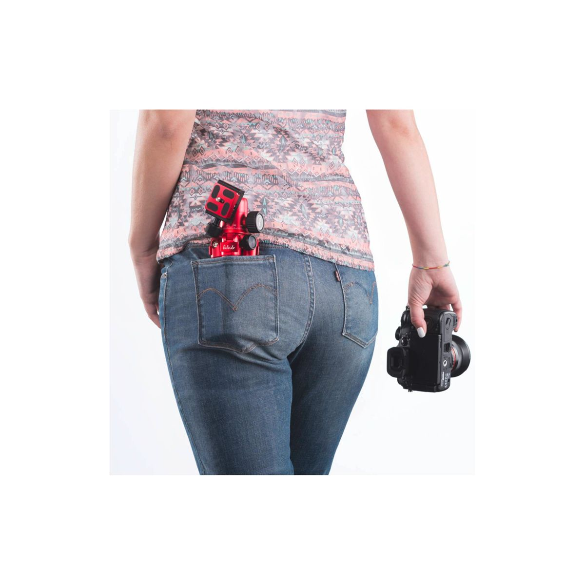 Kobieta z aparatem w tylnej kieszeni dżinsów. Drugi aparat w jej ręce.