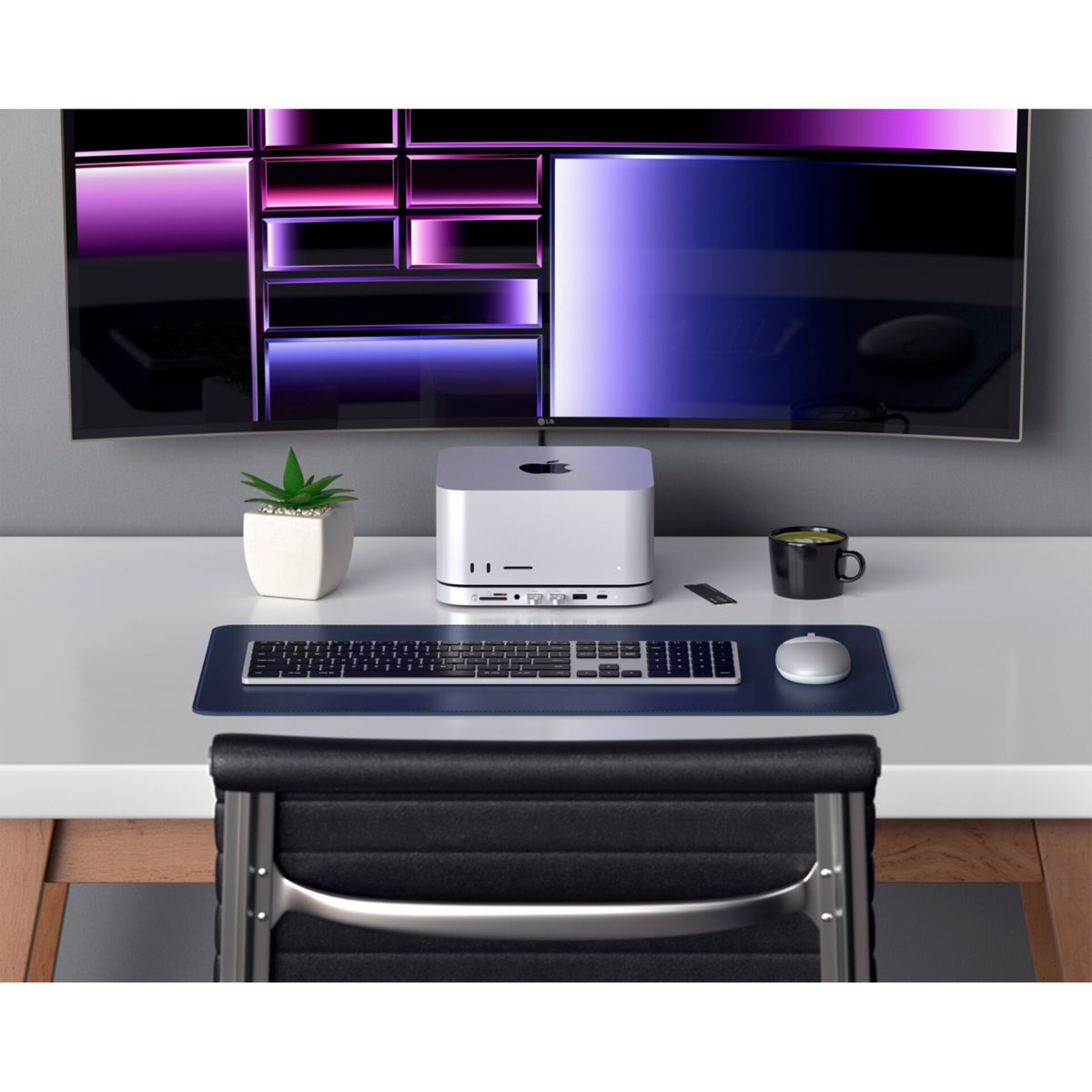 Ein Schreibtisch mit Mac Studio, Monitor, Tastatur und Maus. Es gibt eine Pflanze und eine Kaffeetasse.