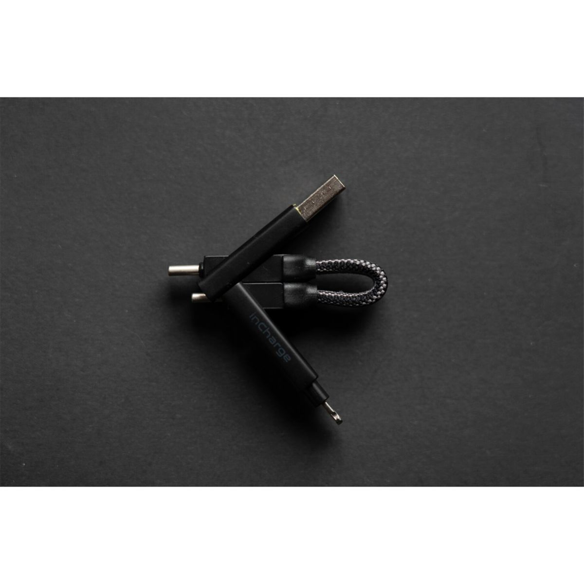 Cavo multi-connettore nero su una superficie nera. Il cavo ha diversi tipi di connettore.