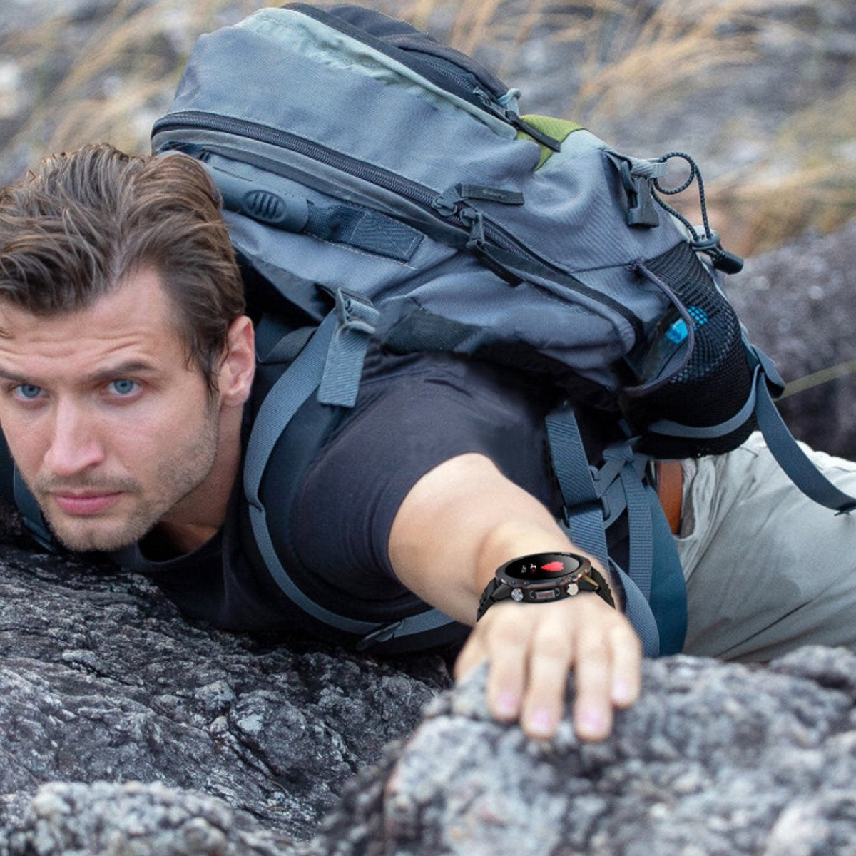 A man with blue eyes wears a smartwatch while climbing on rocks with a backpack.