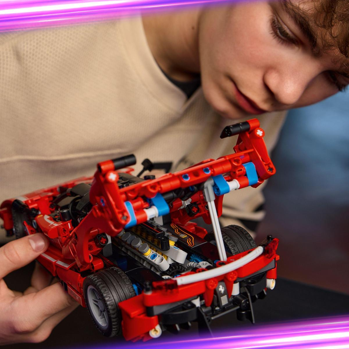 Chłopiec patrzy na czerwony samochód Lego. Samochód ma otwarte niektóre części. Tło to rozmyty pokój.