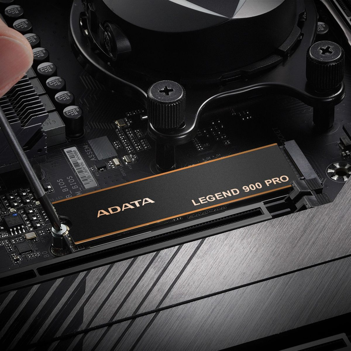 Personne installant un SSD ADATA LEGEND 900 PRO sur une carte mère. SSD noir, logo ADATA doré, vis argentées.