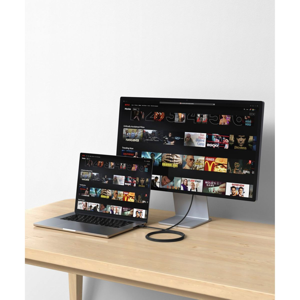Un laptop e un monitor collegati su un tavolo di legno. Il monitor mostra un sito di streaming.
