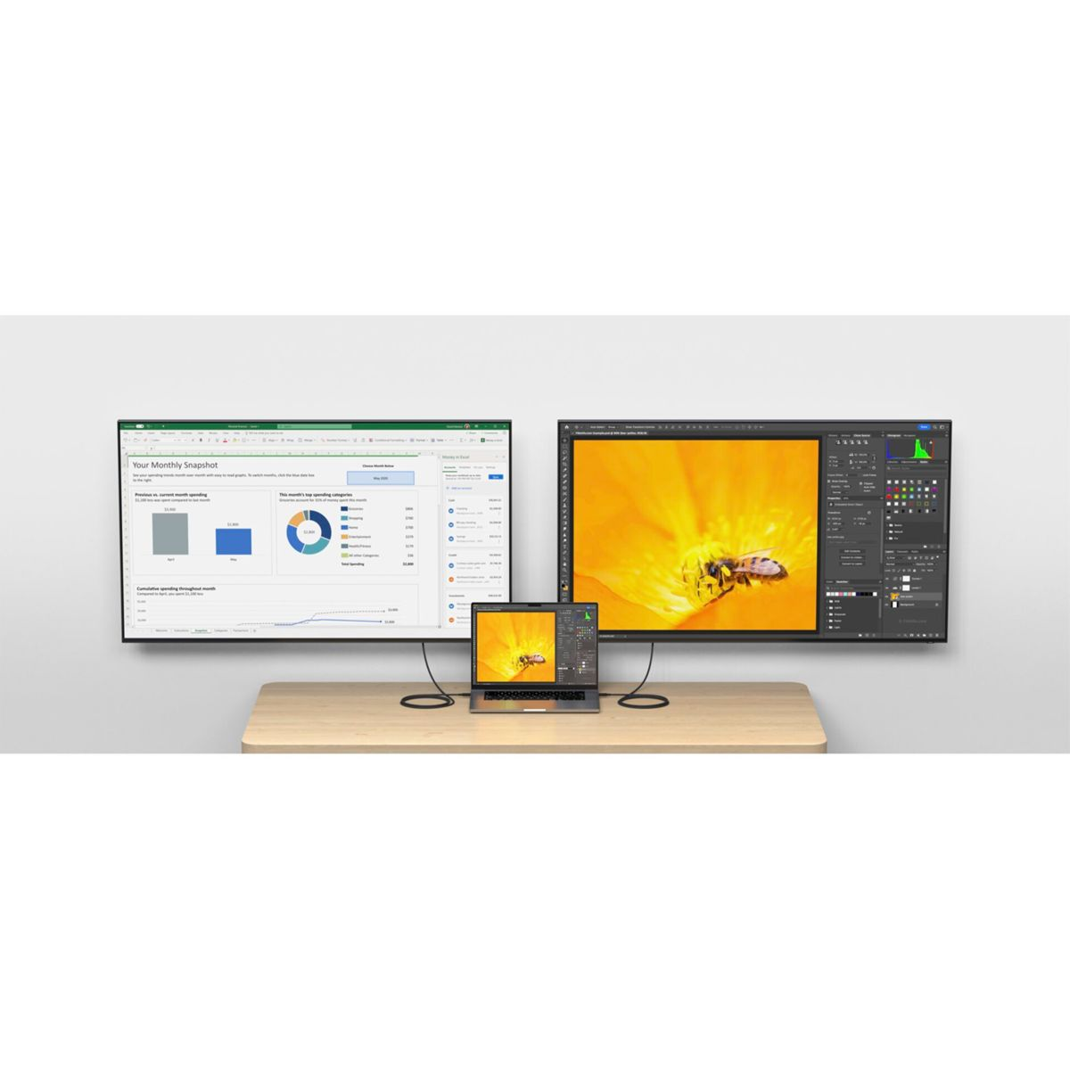 Due monitor mostrano dati e un'ape su un fiore. Laptop sulla scrivania. Sfondo muro bianco. Cavi neri.