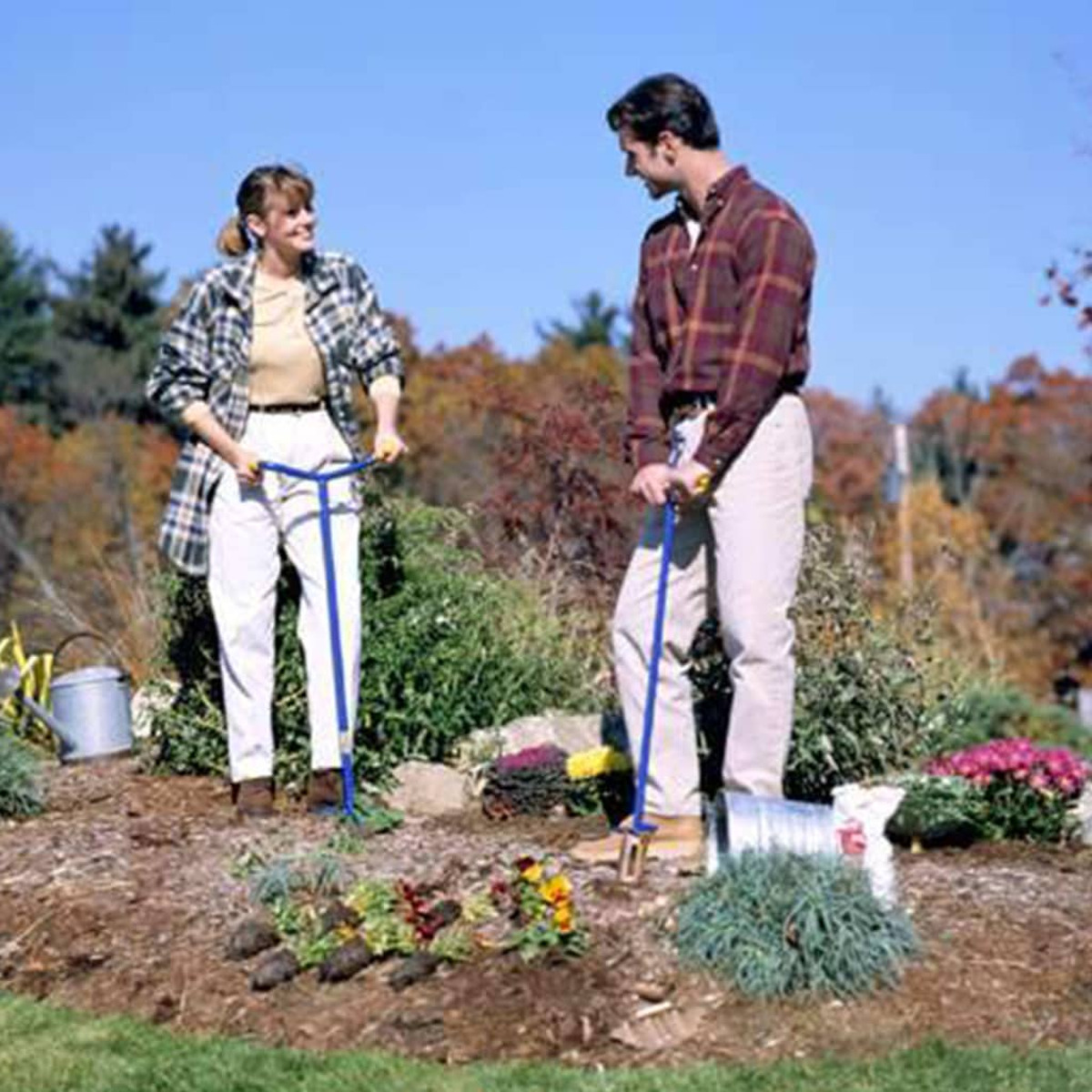 Twee mensen die tuinklauwgereedschap gebruiken in een tuinsetting met bloemen en planten.