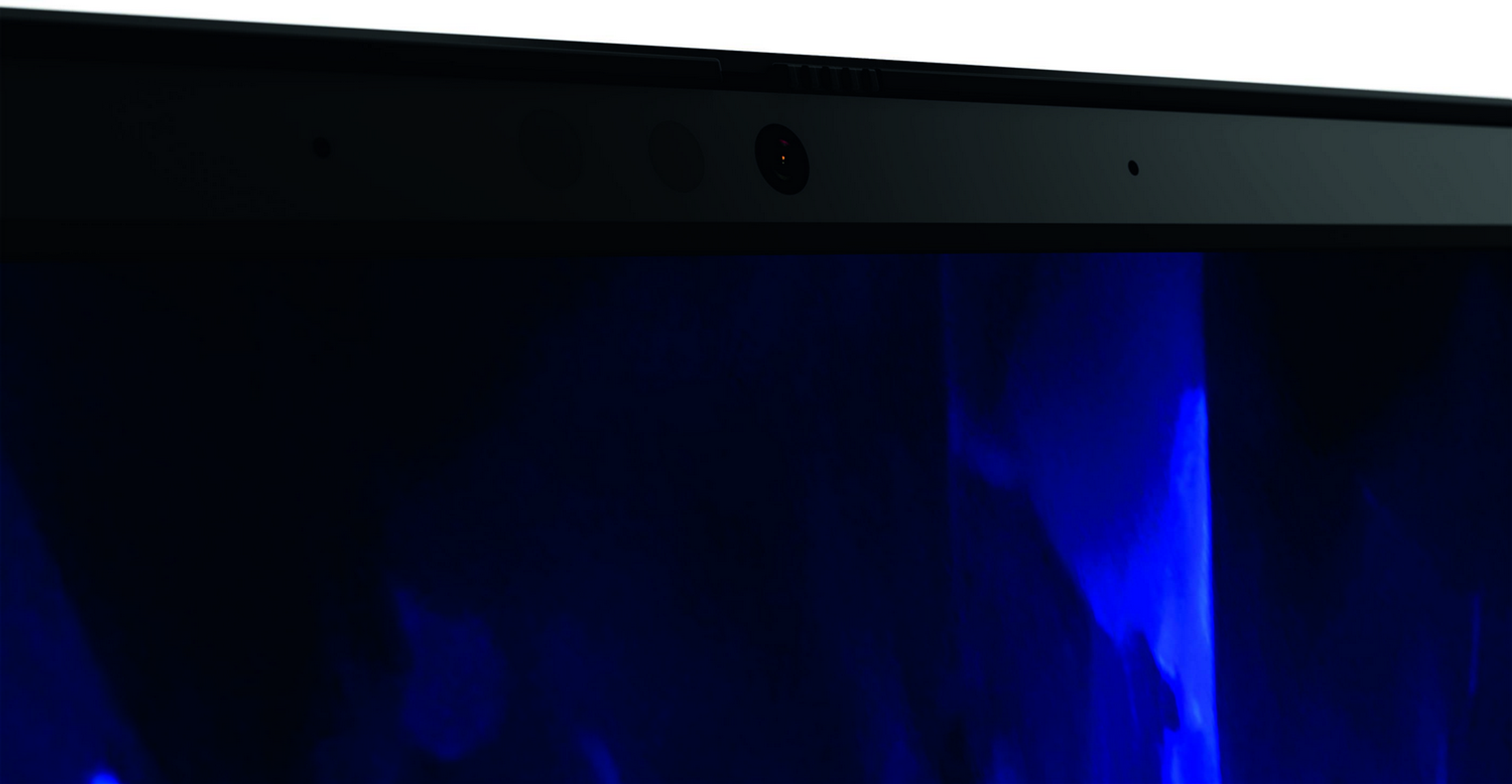 Primer plano del borde superior de la pantalla de un portátil. Una cámara web está centrada y la pantalla es negra y azul.