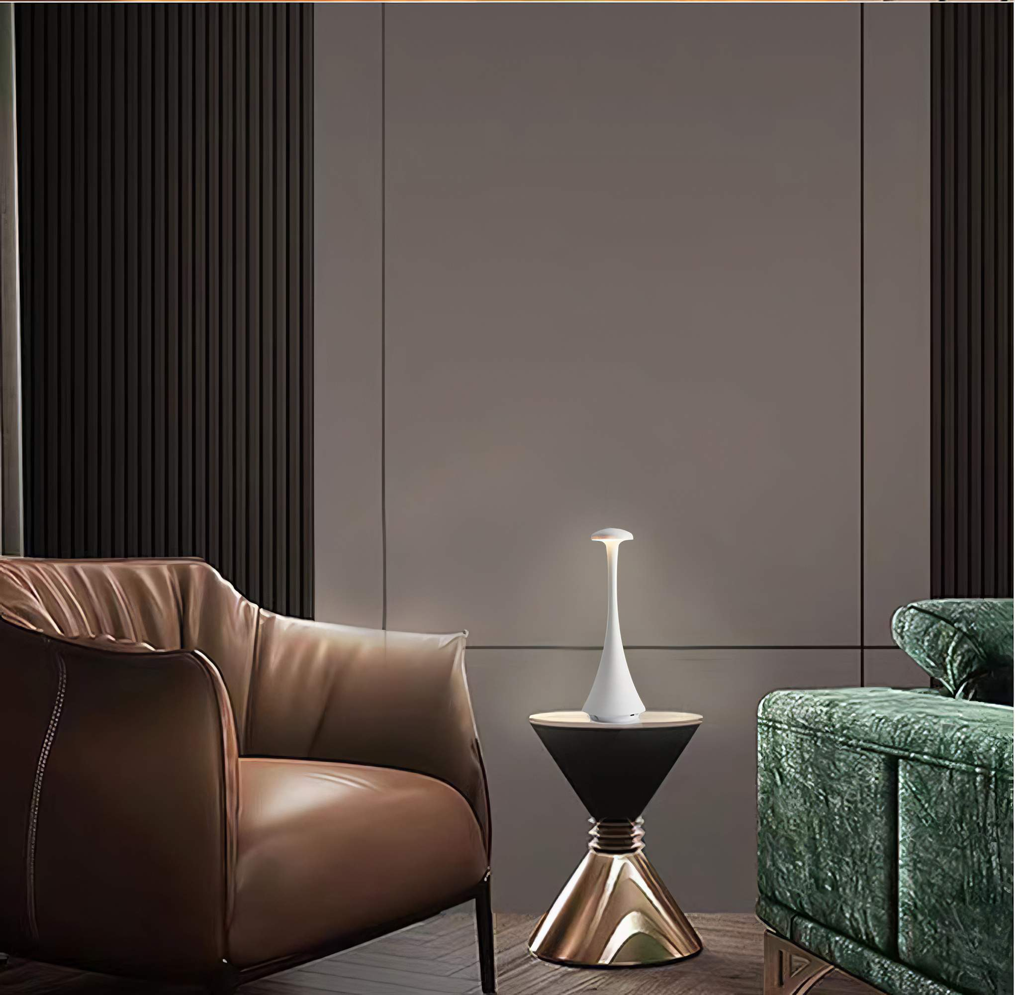 Eine weiße Lampe mit schlankem Hals und rundem Oberteil auf einem schwarz-goldenen Tisch. Dahinter steht ein grünes Sofa.