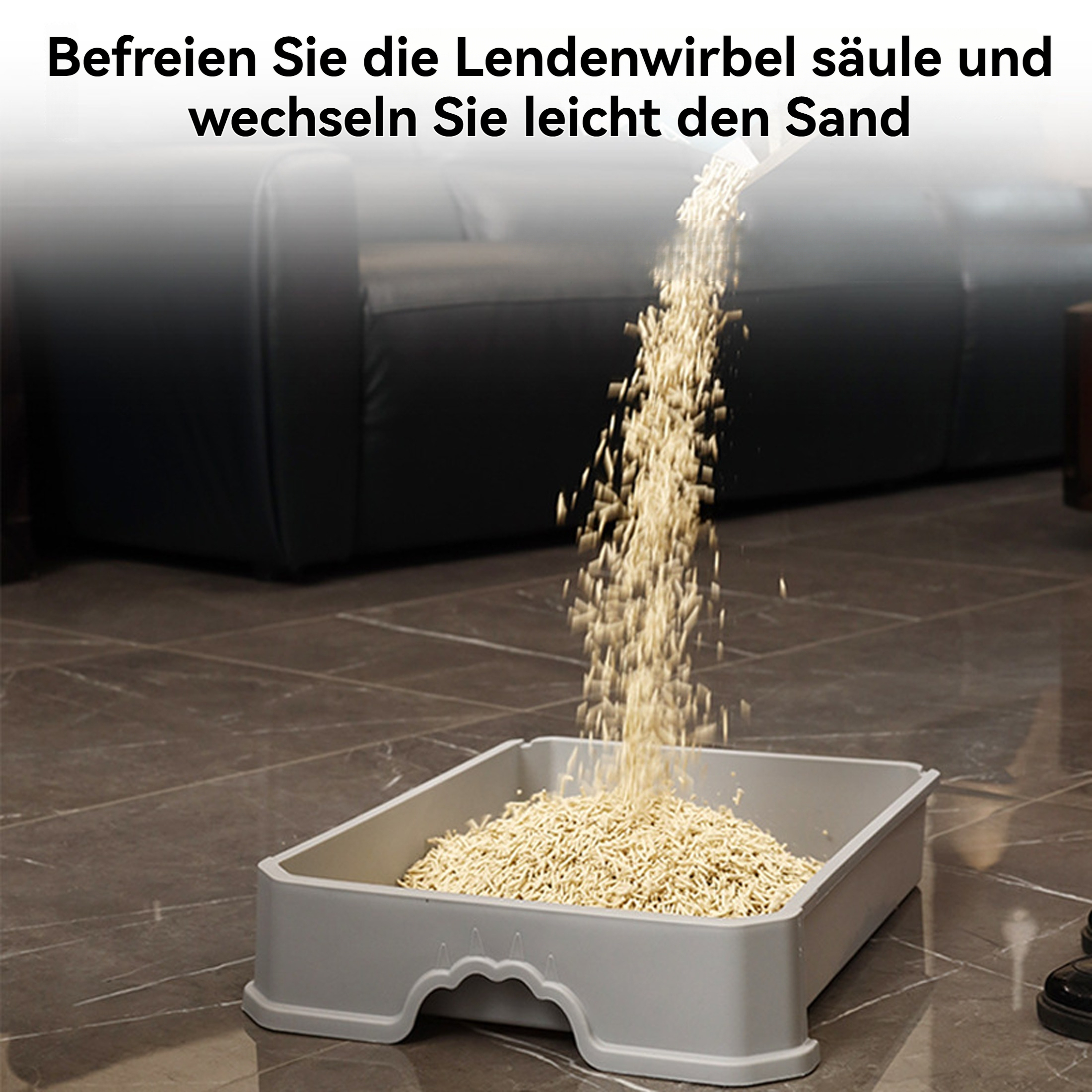 Sand wird in graue Katzentoilette gegossen. Box am Boden, Sofa im Hintergrund.