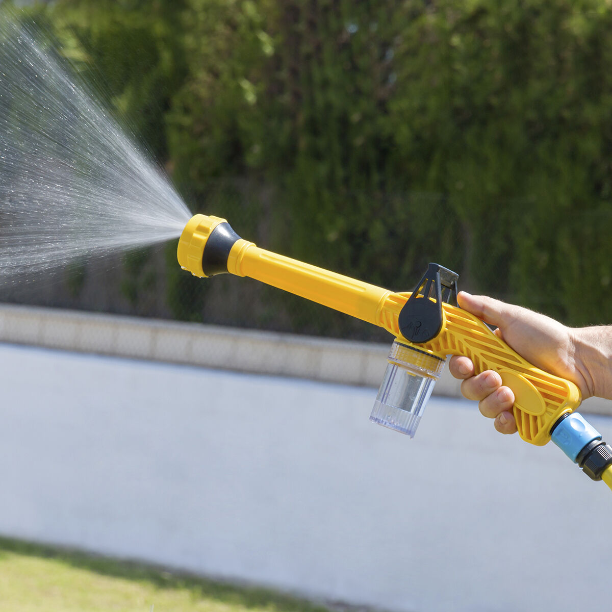 Eine Person hält eine gelbe Wasserspritzpistole. Wasser wird in die Luft gespritzt.