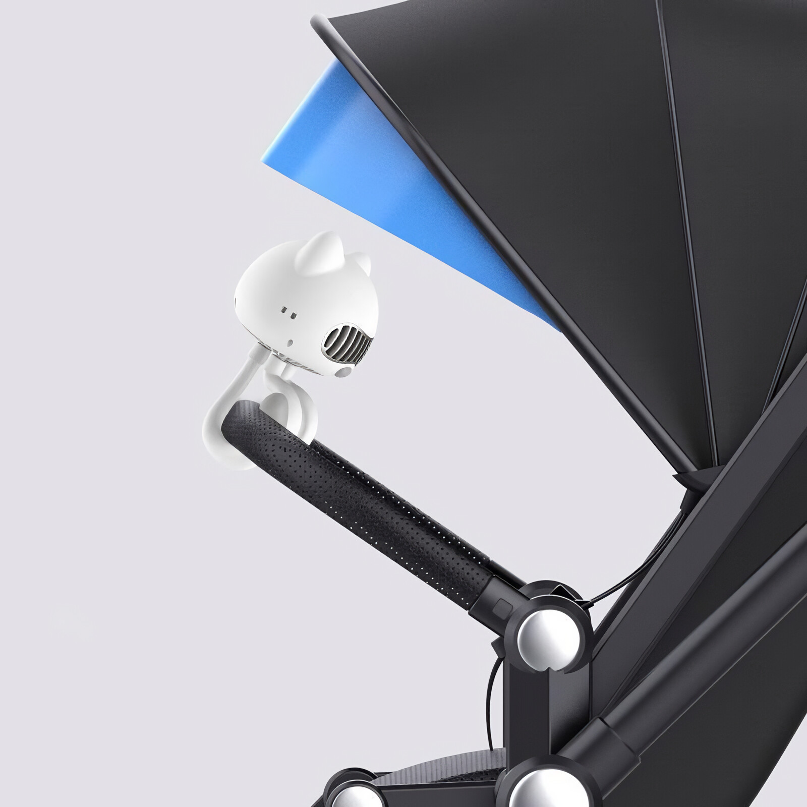 Weißer katzenförmiger Ventilator an einem schwarzen Kinderwagengriff vor hellem Hintergrund befestigt.