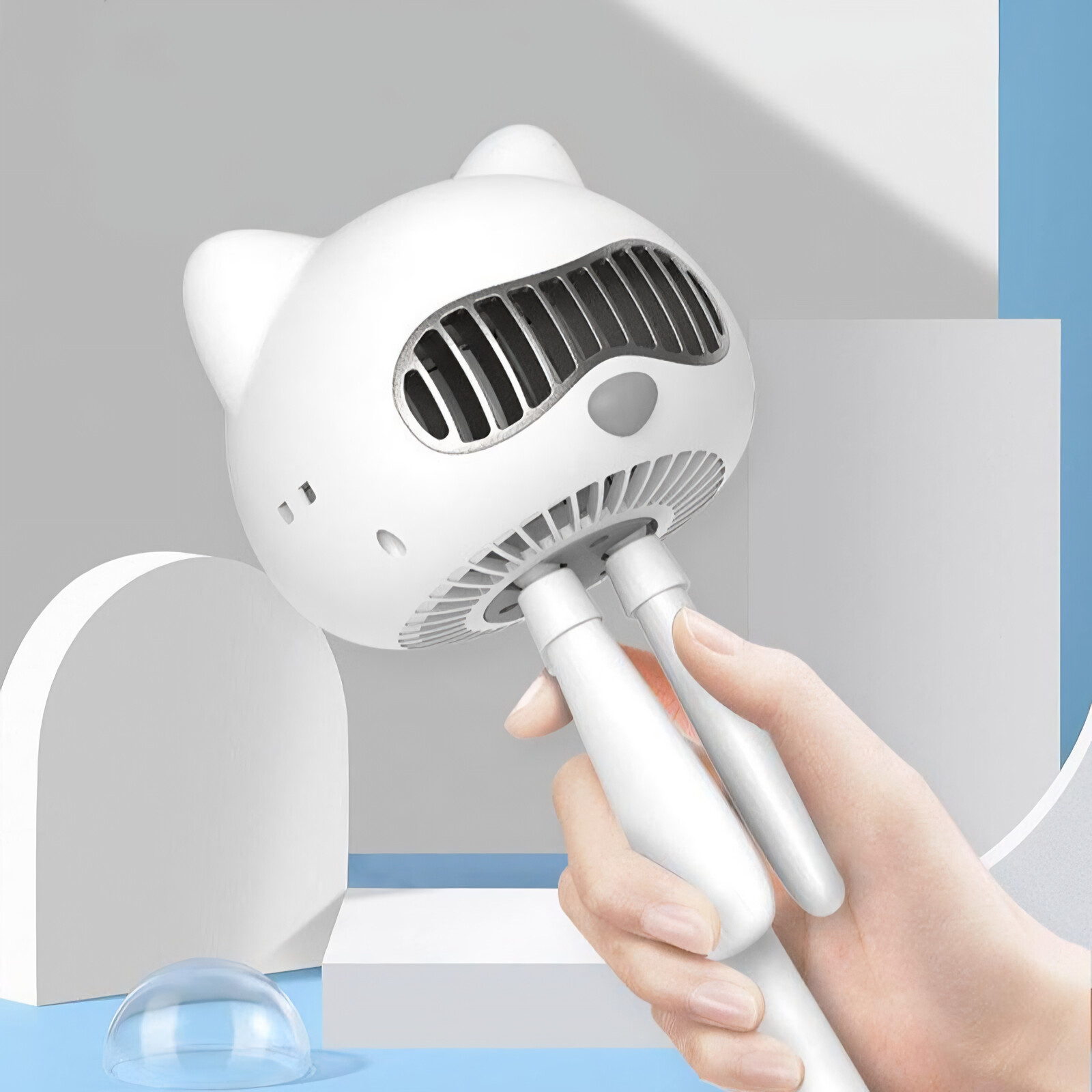 Weißer katzenförmiger Ventilator, gehalten von einer Hand, mit einer transparenten Kuppel und weißem Hintergrund.